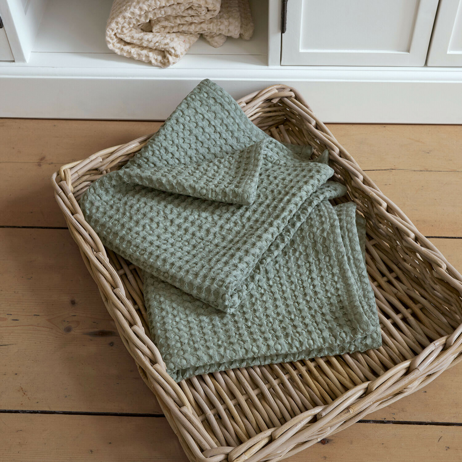 Coppia di asciugamani Maralei Coperta verde in cotone con trama a nido d'ape in cesto di vimini su pavimento in legno