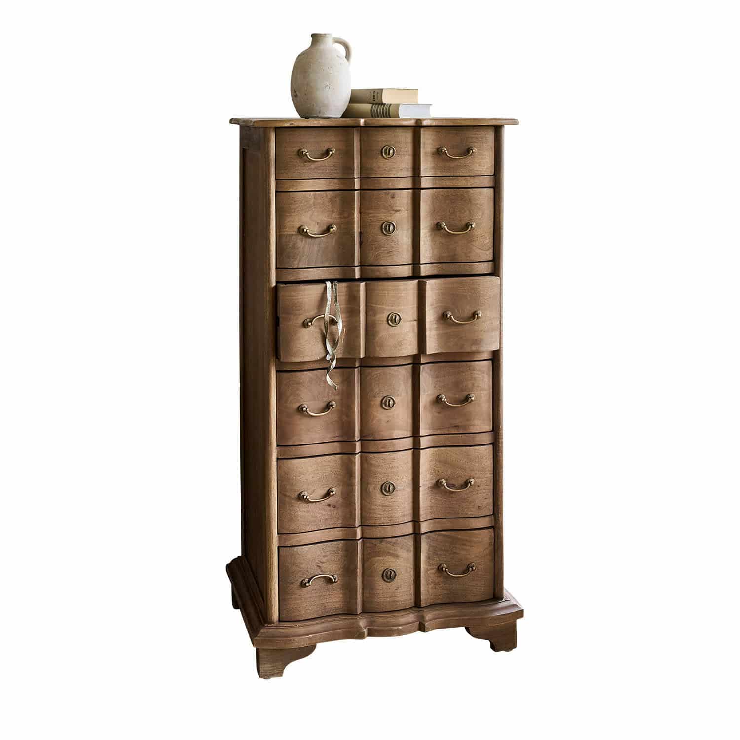 Cassettiera Aiguillon Cassettiera alta in legno naturale con molti cassetti e brocca in ceramica sopra libri