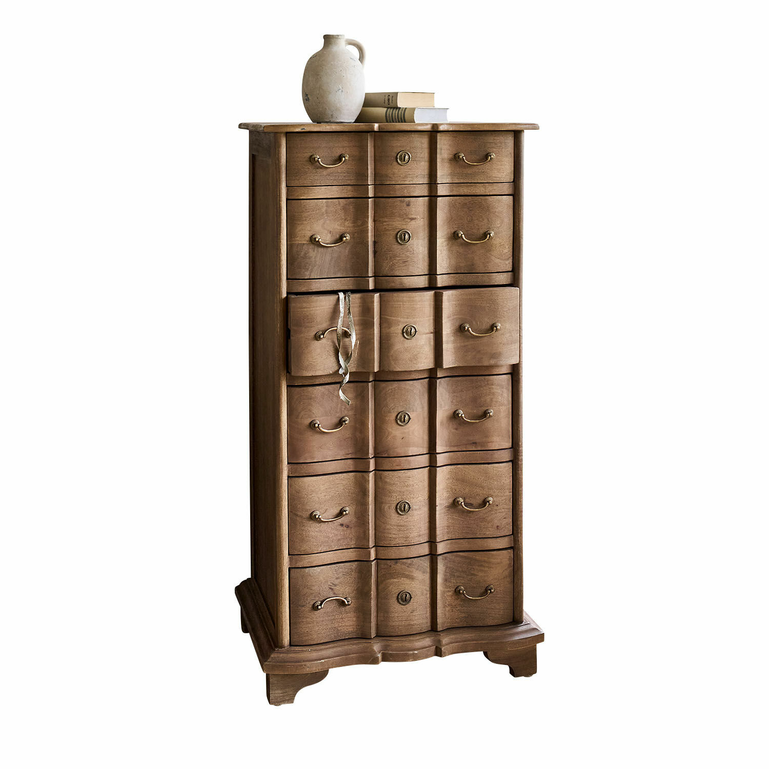 Cassettiera Aiguillon Cassettiera alta in legno naturale con molti cassetti e brocca in ceramica sopra libri