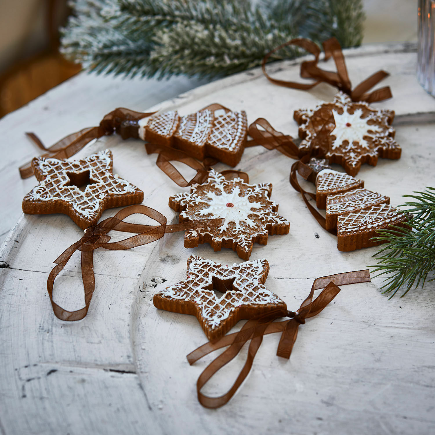 Set di 6 ciondoli Chimayo Set di decorazioni natalizie in pan di zenzero con glassa bianca e nastri marroni su tavolo in legno