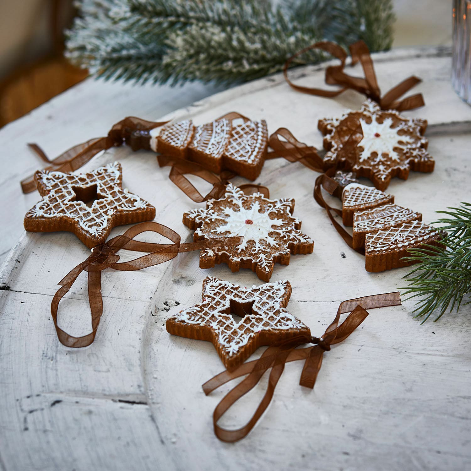 Set di 6 ciondoli Chimayo Set di decorazioni natalizie in pan di zenzero con glassa bianca e nastri marroni su tavolo in legno