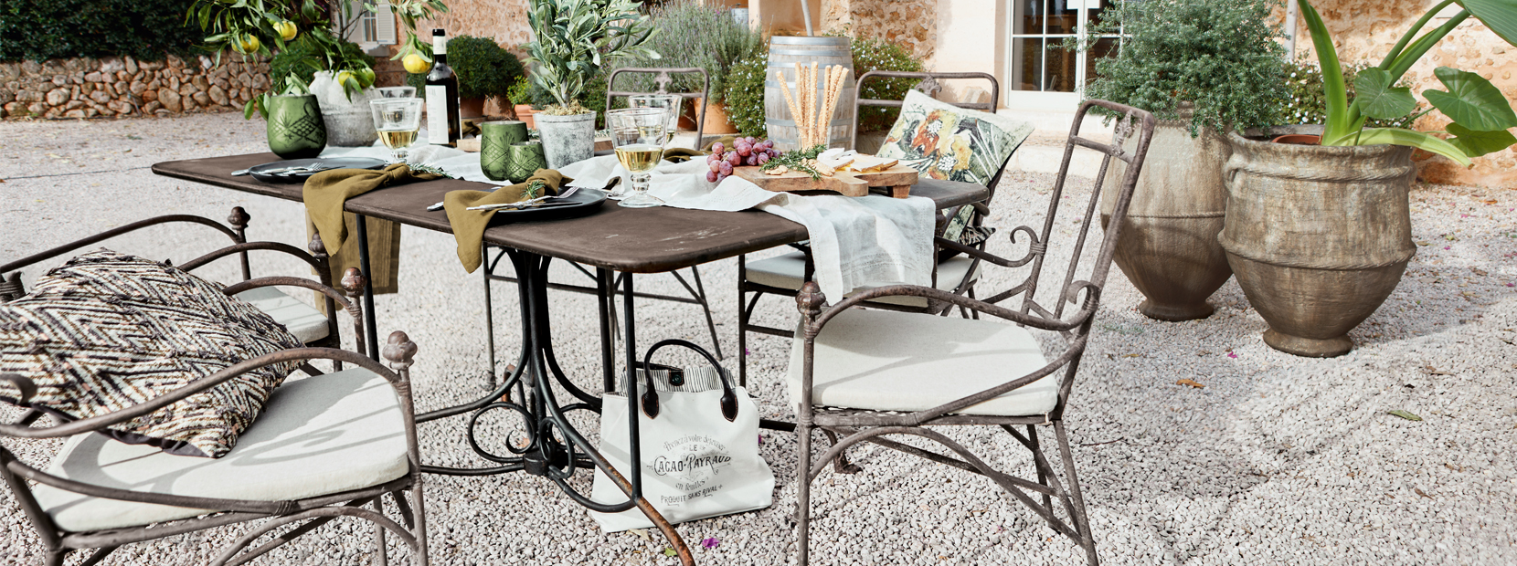 Tavolo da giardino con sedie in metallo e decorazioni mediterranee su patio ghiaioso