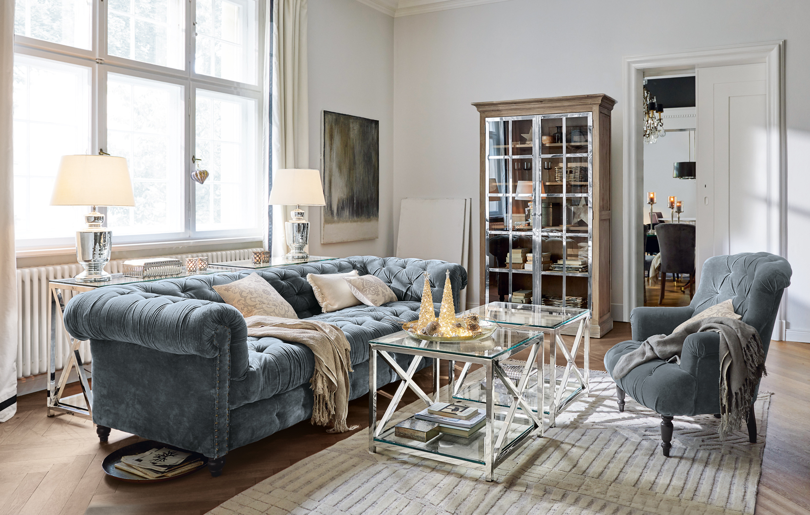 Soggiorno elegante con divano in velluto blu e tavolini in vetro in stile classico