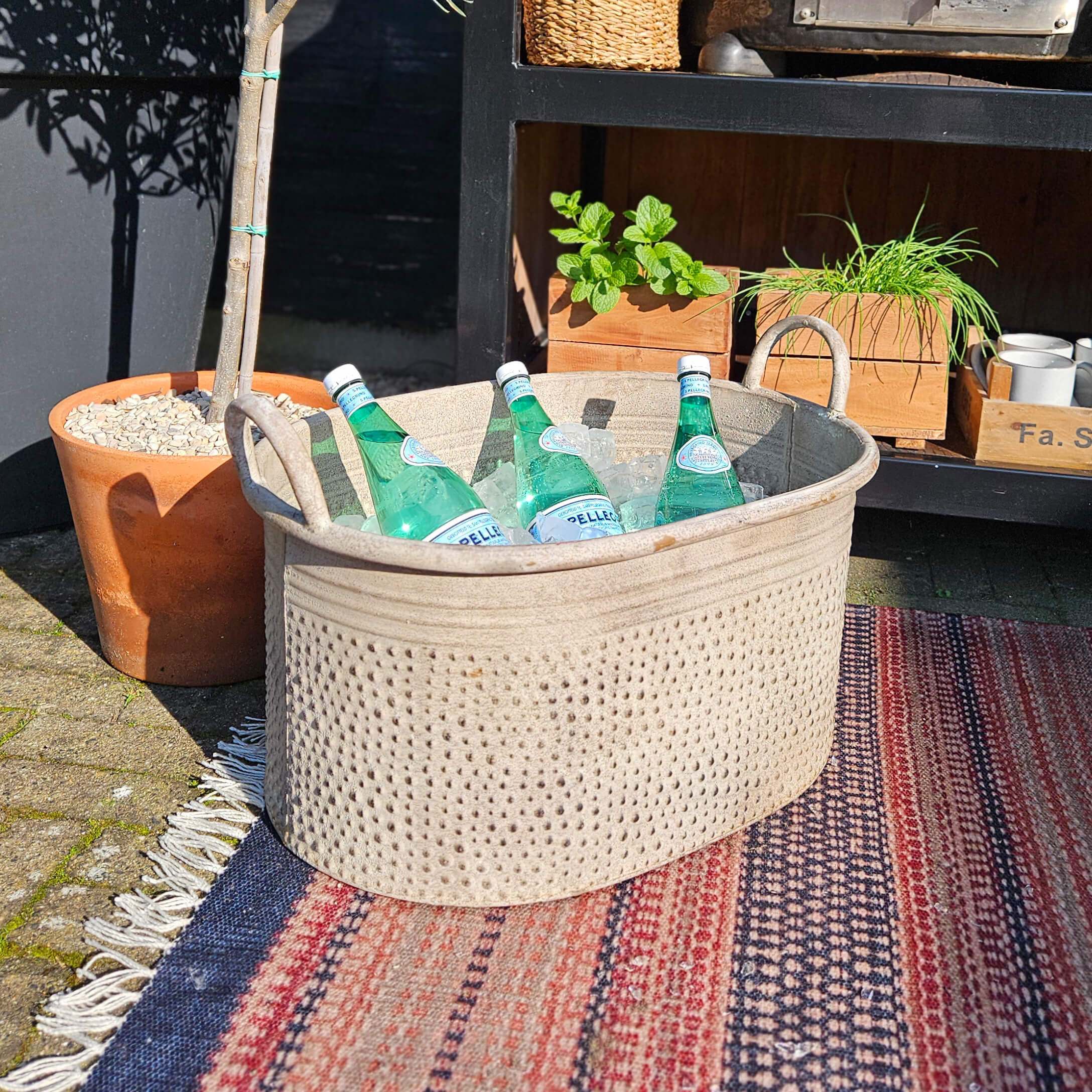 Contenitore beige in tessuto con manici con bottiglie d'acqua minerale su ghiaccio all'aperto