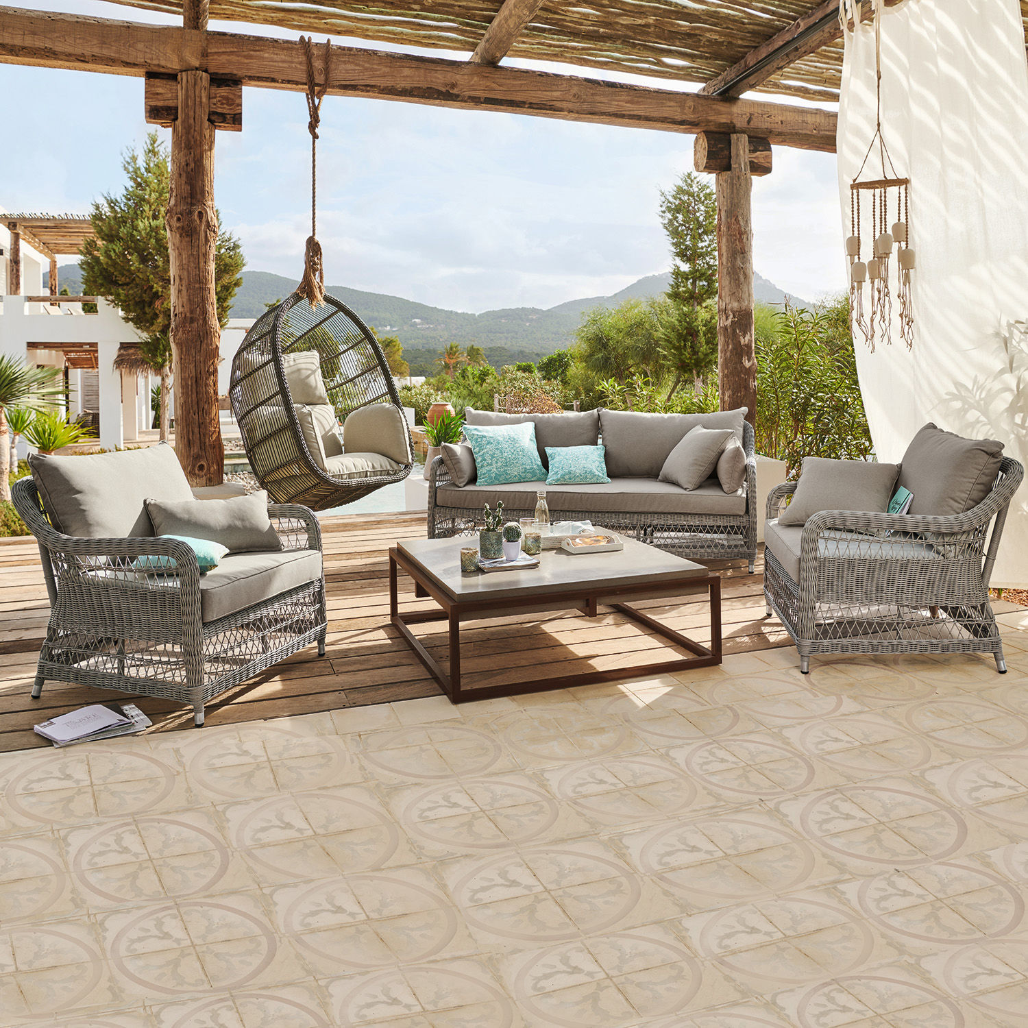 Salotto Tanaiste Set di mobili da giardino in rattan grigio con cuscini e poltrona sospesa su terrazza con vista montagna