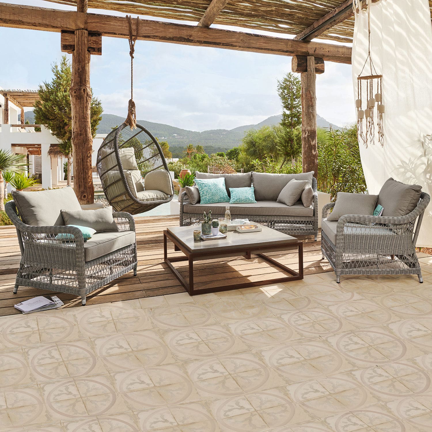 Salotto Tanaiste Set di mobili da giardino in rattan grigio con cuscini e poltrona sospesa su terrazza con vista montagna
