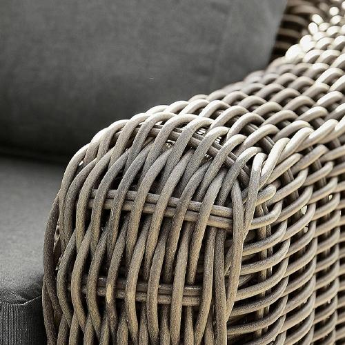 Dettaglio di bracciolo intrecciato marrone in materiale sintetico su mobile da giardino con cuscino grigio