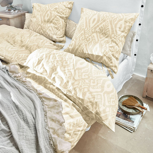 Biancheria da letto beige con motivo geometrico in tessuto morbido su letto in stanza luminosa