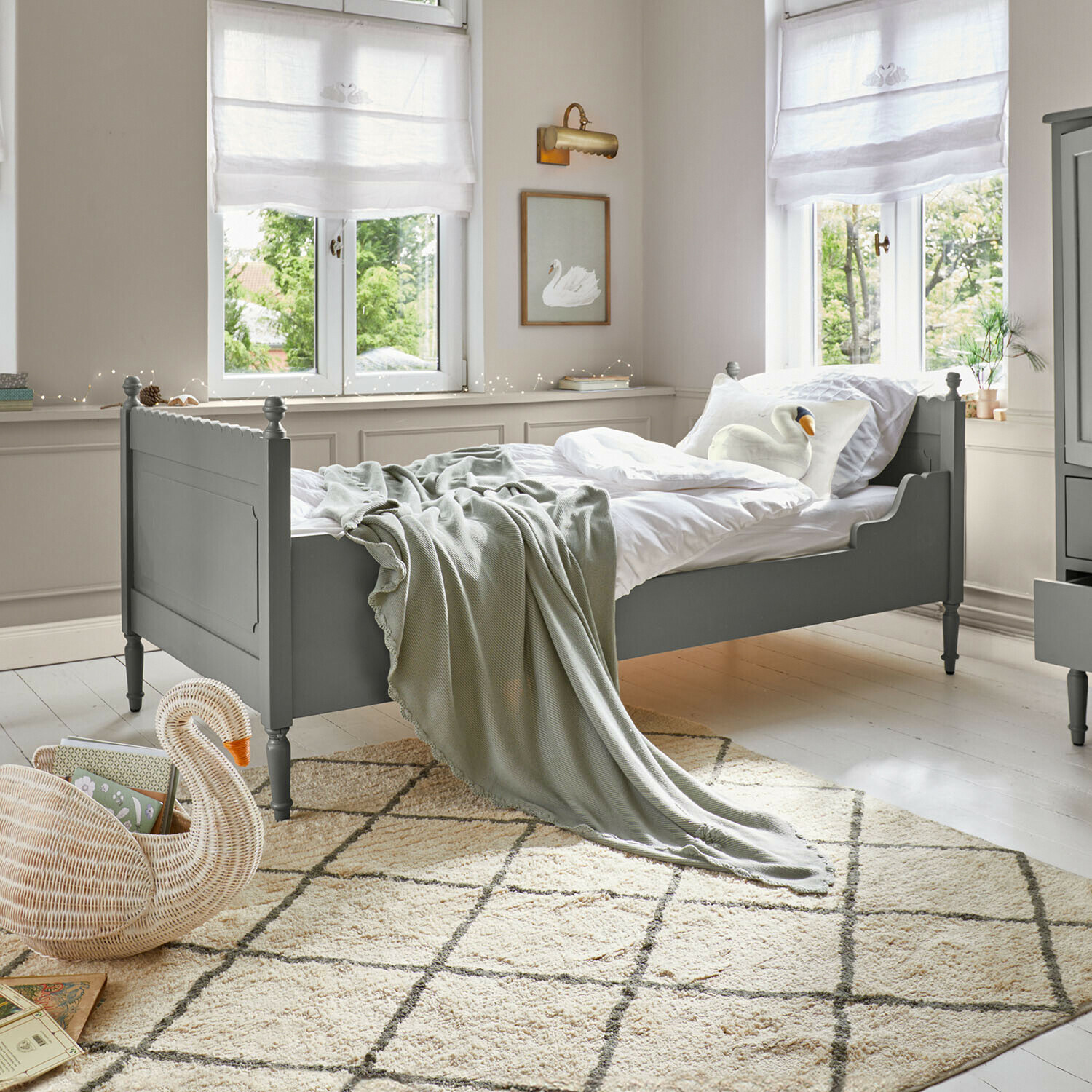 Letto singolo Kystlund Letto in legno verde con biancheria bianca e coperta grigia in stanza luminosa con tappeto