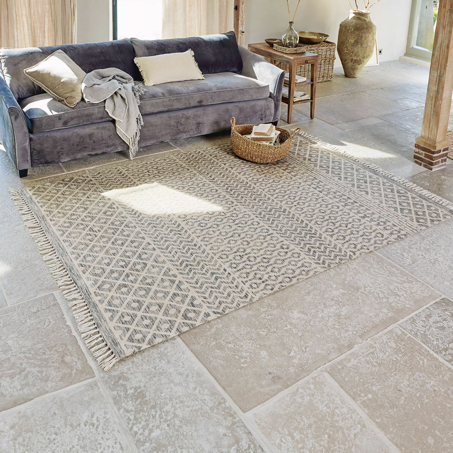 Tappeto per interni ed esterni Champigny Tappeto beige con motivo geometrico e frange su pavimento in pietra in soggiorno luminoso