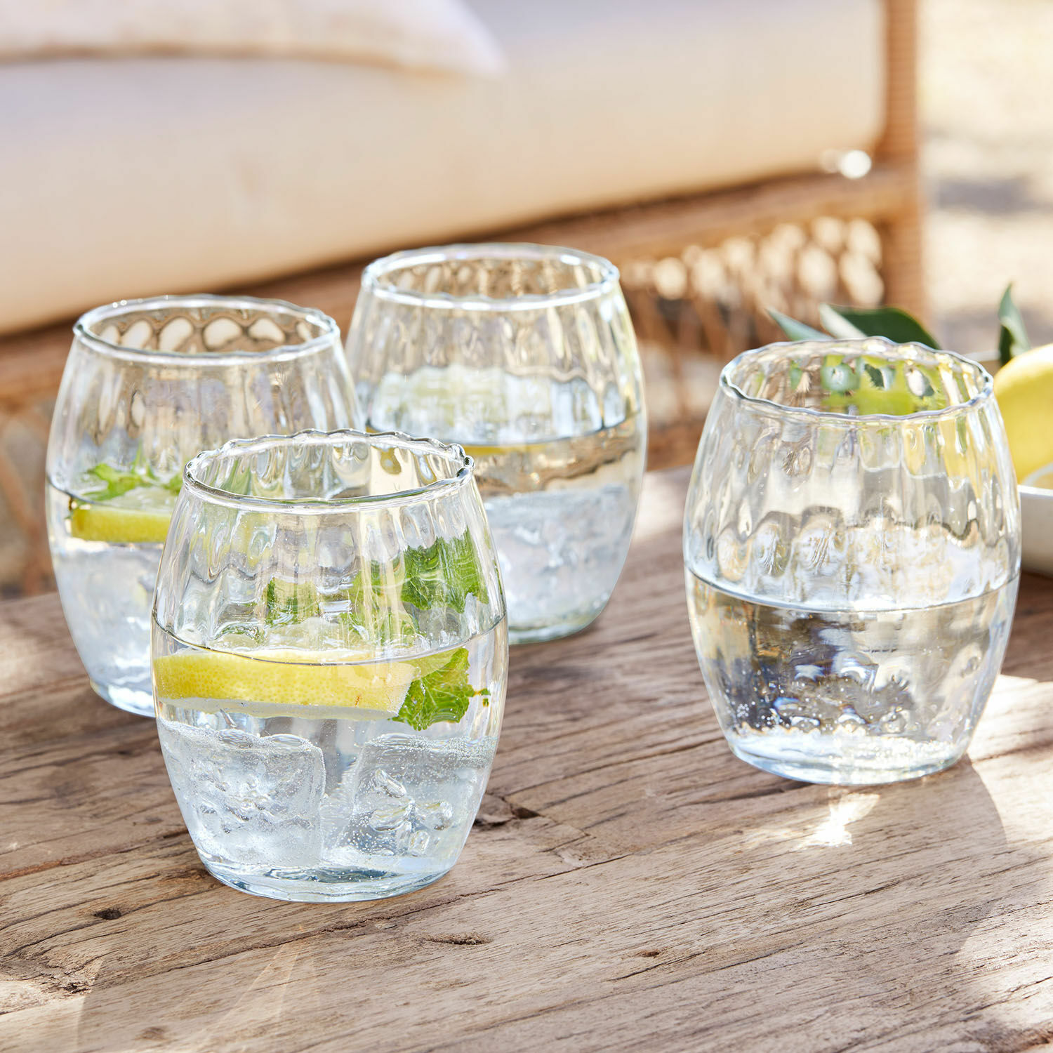 Set di 4 bicchieri Bourgavin Set di quattro bicchieri in vetro trasparente con acqua, ghiaccio e limone su tavolo di legno