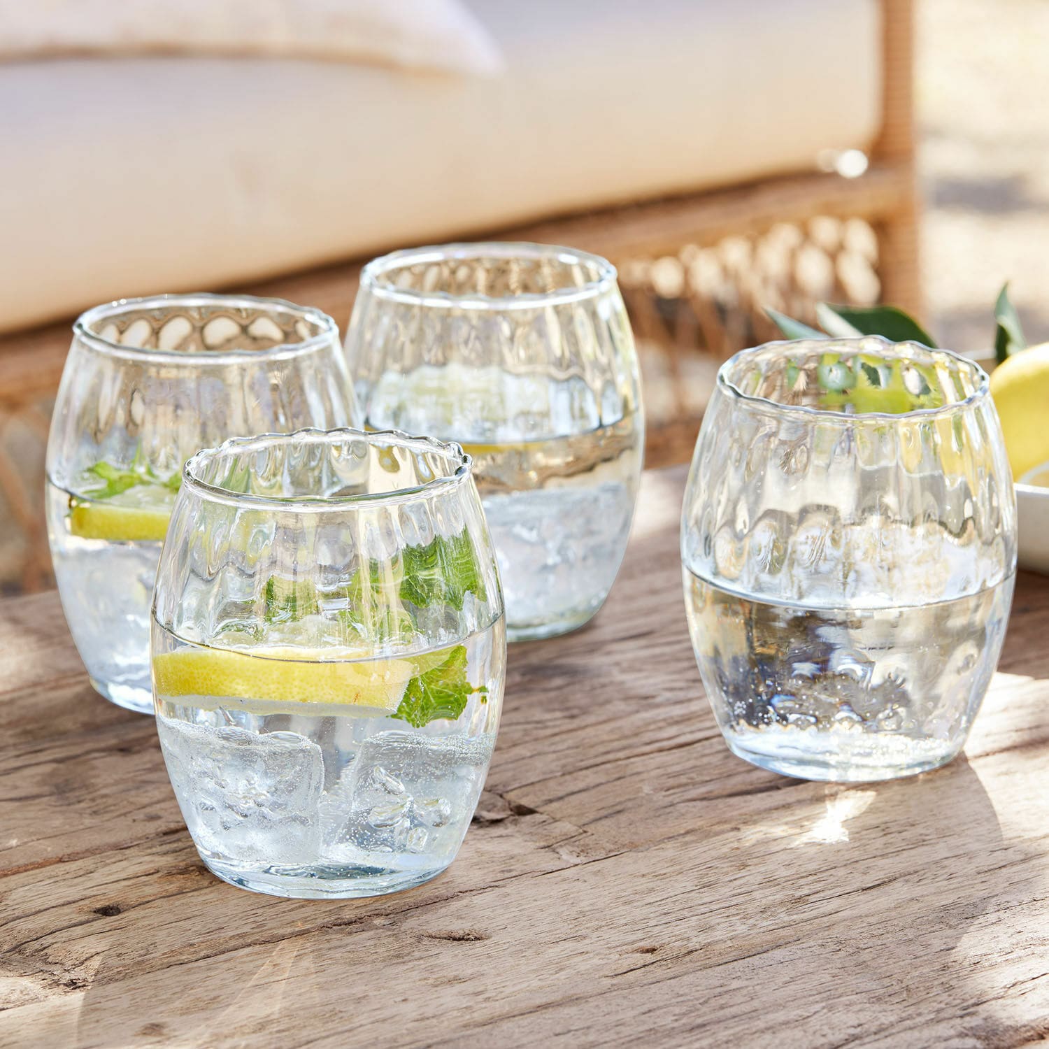 Set di 4 bicchieri Bourgavin Set di quattro bicchieri in vetro trasparente con acqua, ghiaccio e limone su tavolo di legno