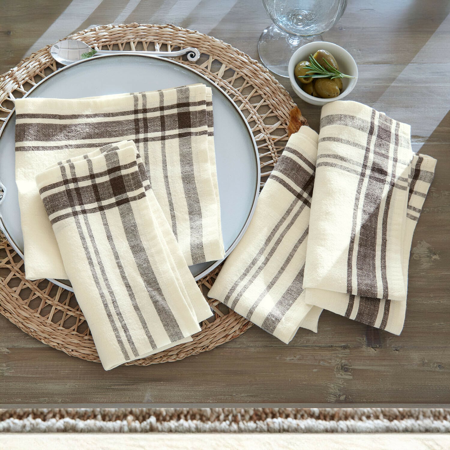 Set di 4 tovaglioli Ellory Tovaglioli in lino crema con motivo a quadri marroni su tavolo rustico in legno