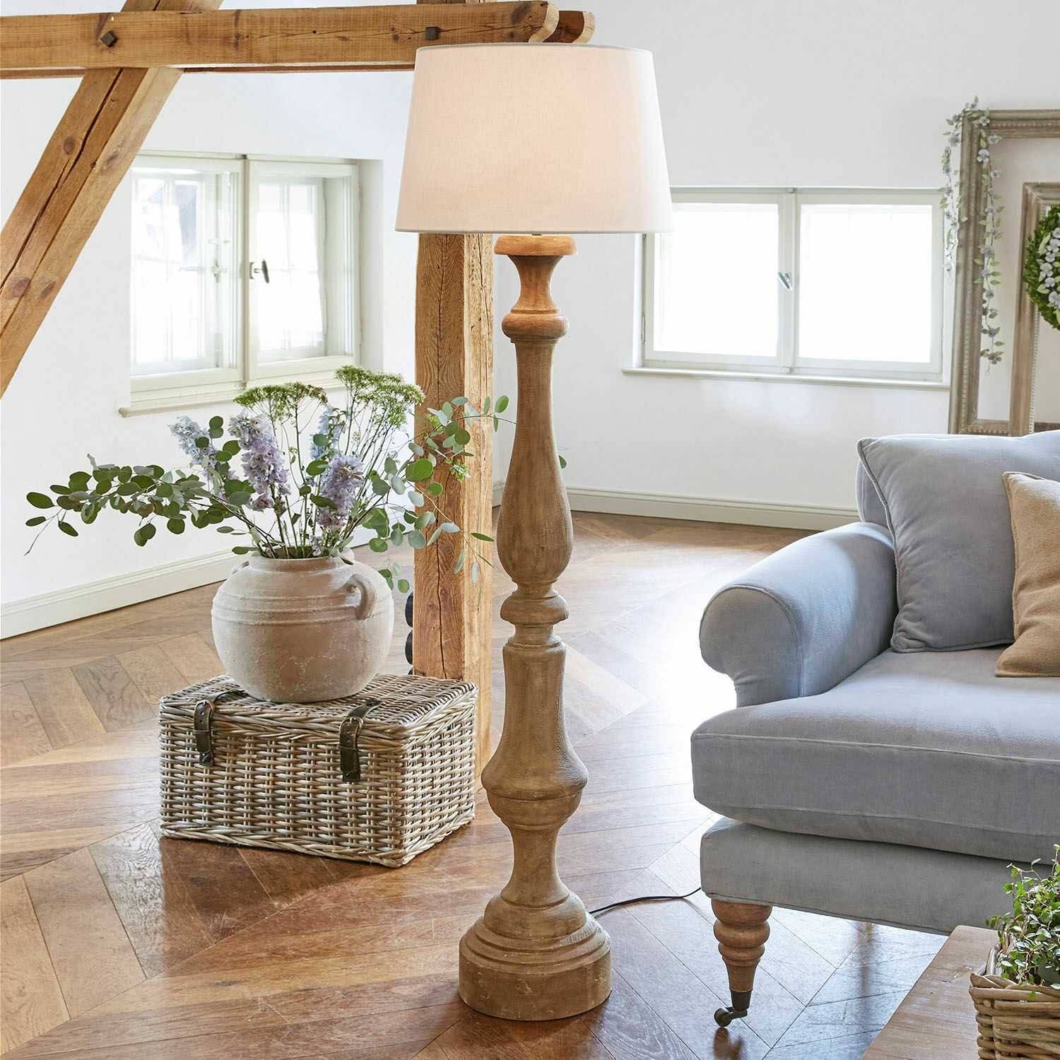 Lampada a stelo Etienne Lampada da terra in legno con paralume bianco in soggiorno luminoso con divano blu e cesto in vimini