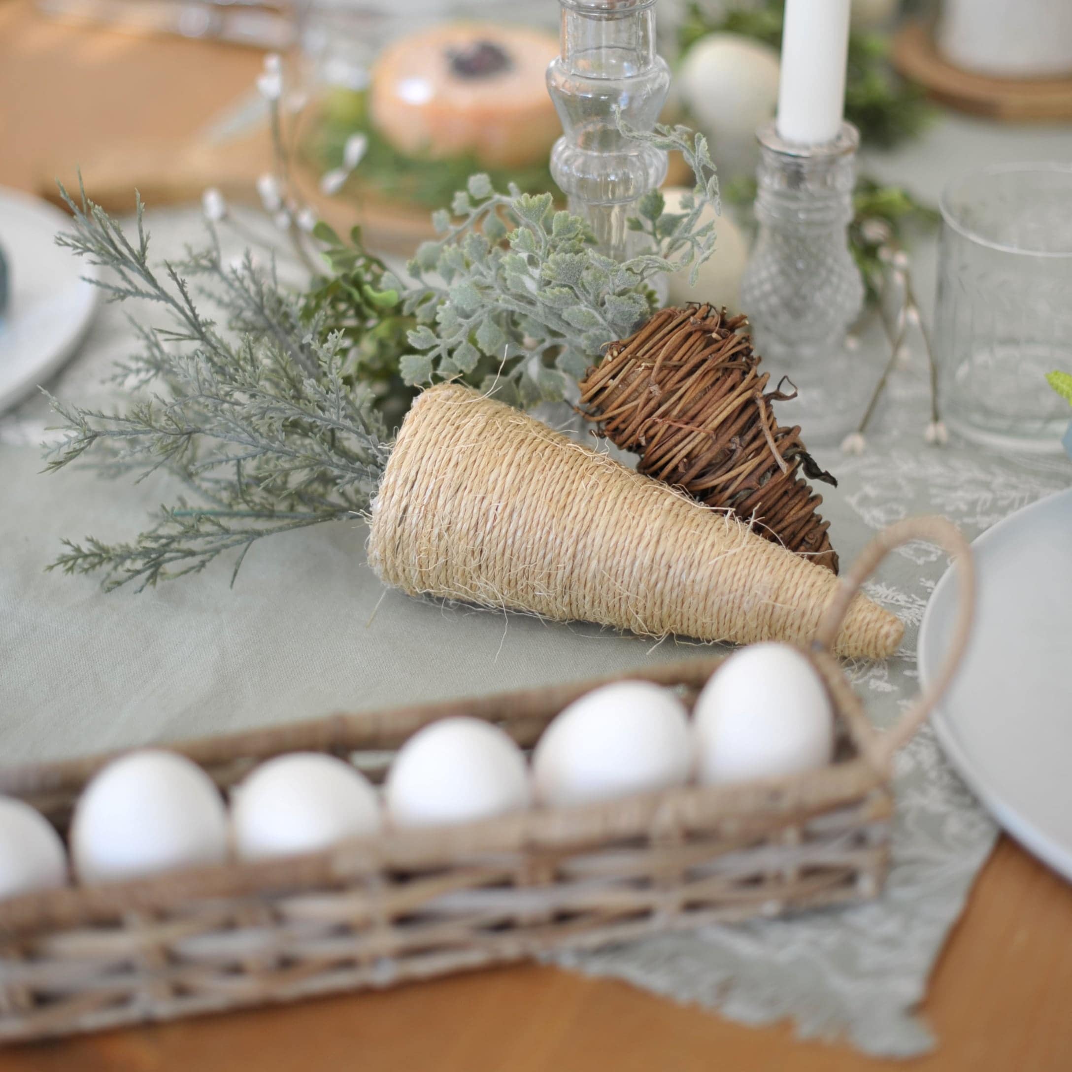 Coni decorativi in materiali naturali con rami verdi su tavola festiva