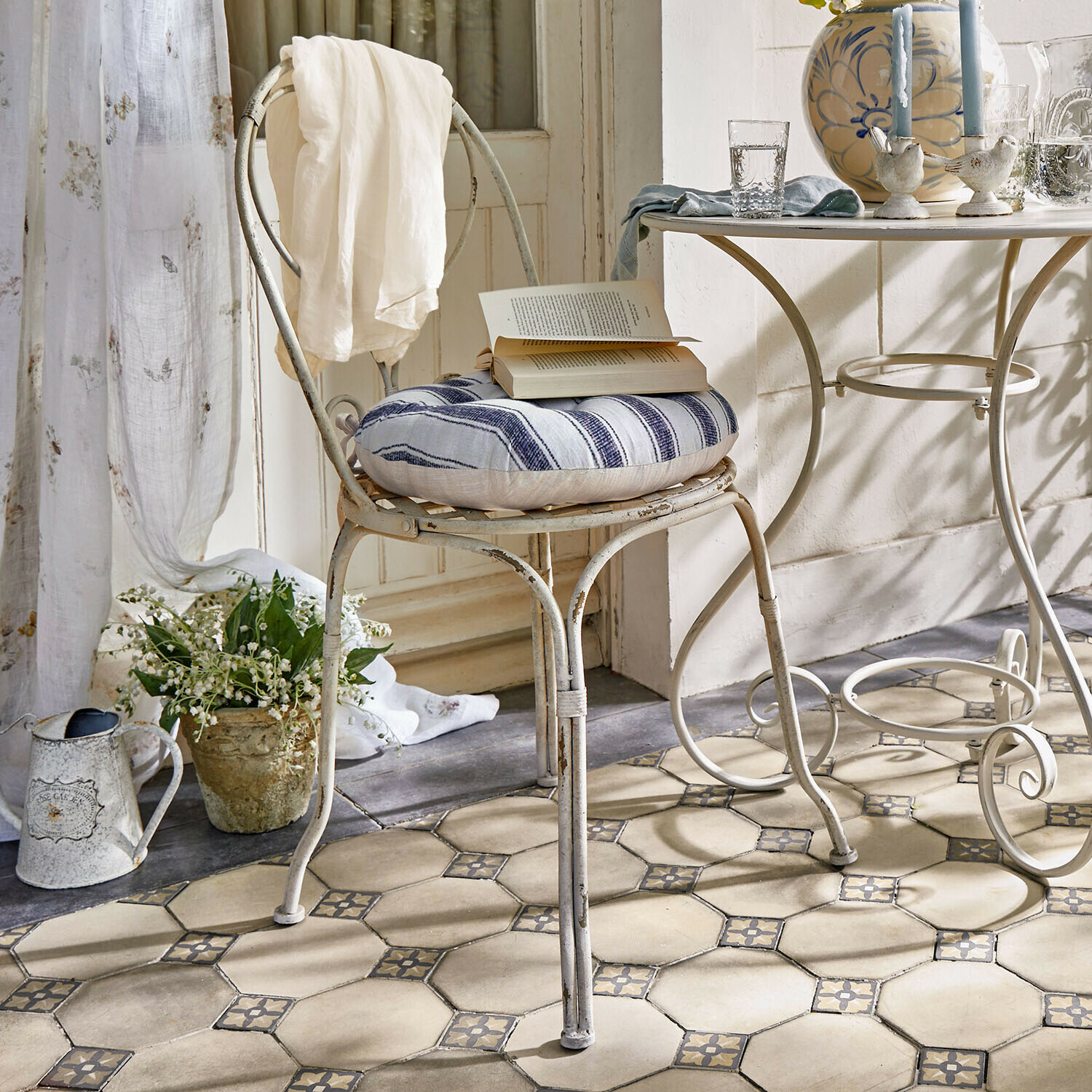 Sedia Aube Sedia vintage in metallo con cuscino a righe blu e bianco e tessuto bianco sullo schienale in ambiente luminoso