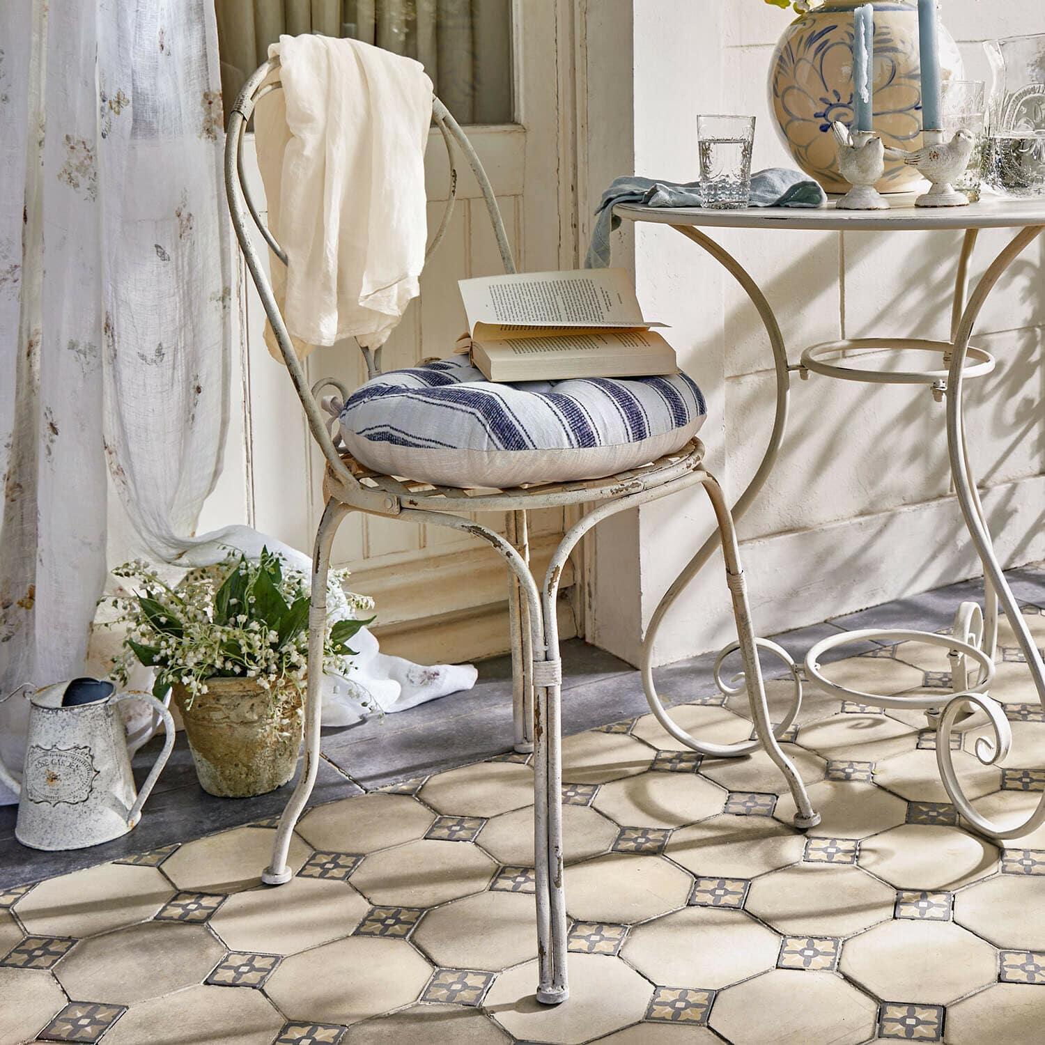 Sedia Aube Sedia vintage in metallo con cuscino a righe blu e bianco e tessuto bianco sullo schienale in ambiente luminoso