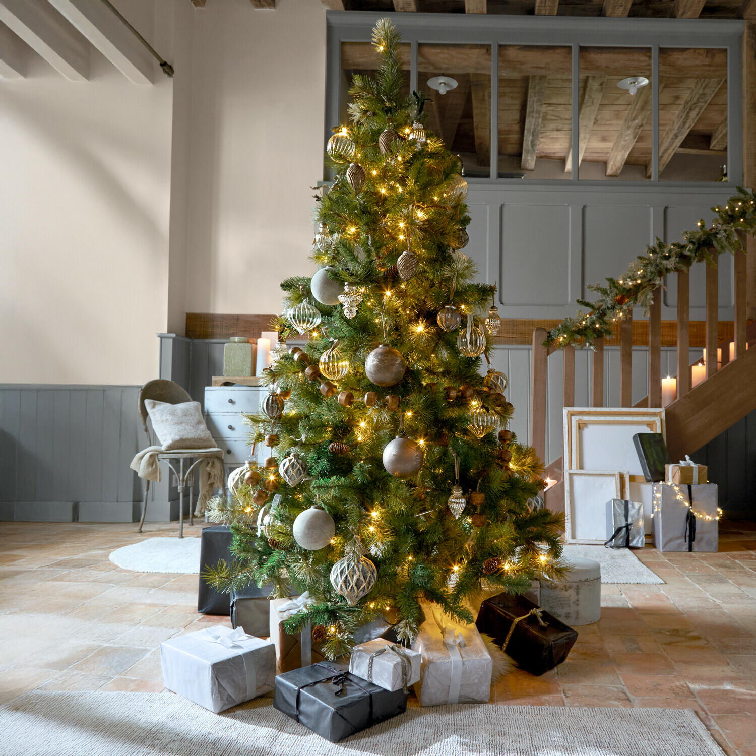 Albero di Natale Aure Albero di Natale decorato con rami verdi e luci dorate in ambiente accogliente con regali