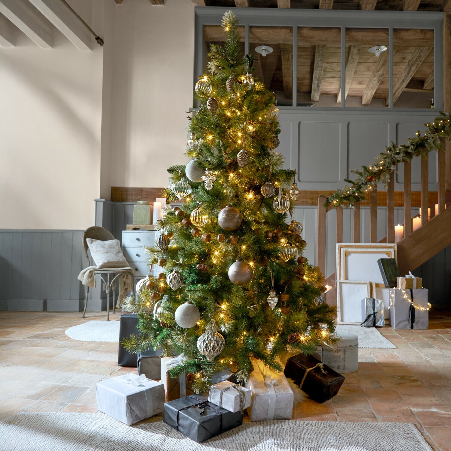 Albero di Natale Aure Albero di Natale decorato con rami verdi e luci dorate in ambiente accogliente con regali