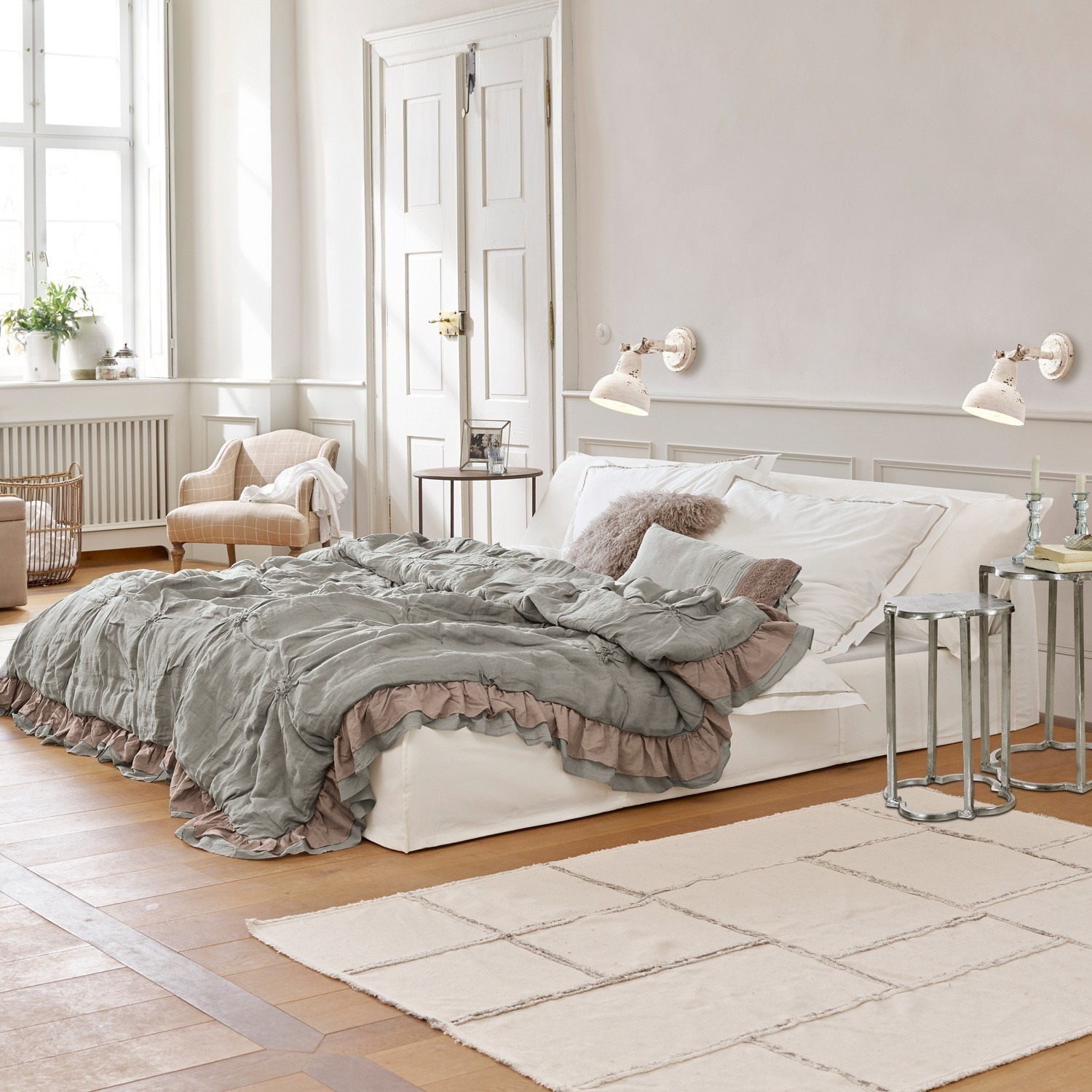 Letto Cottonwood Camera accogliente con letto bianco e coperta grigio-verde con volant su pavimento in legno chiaro