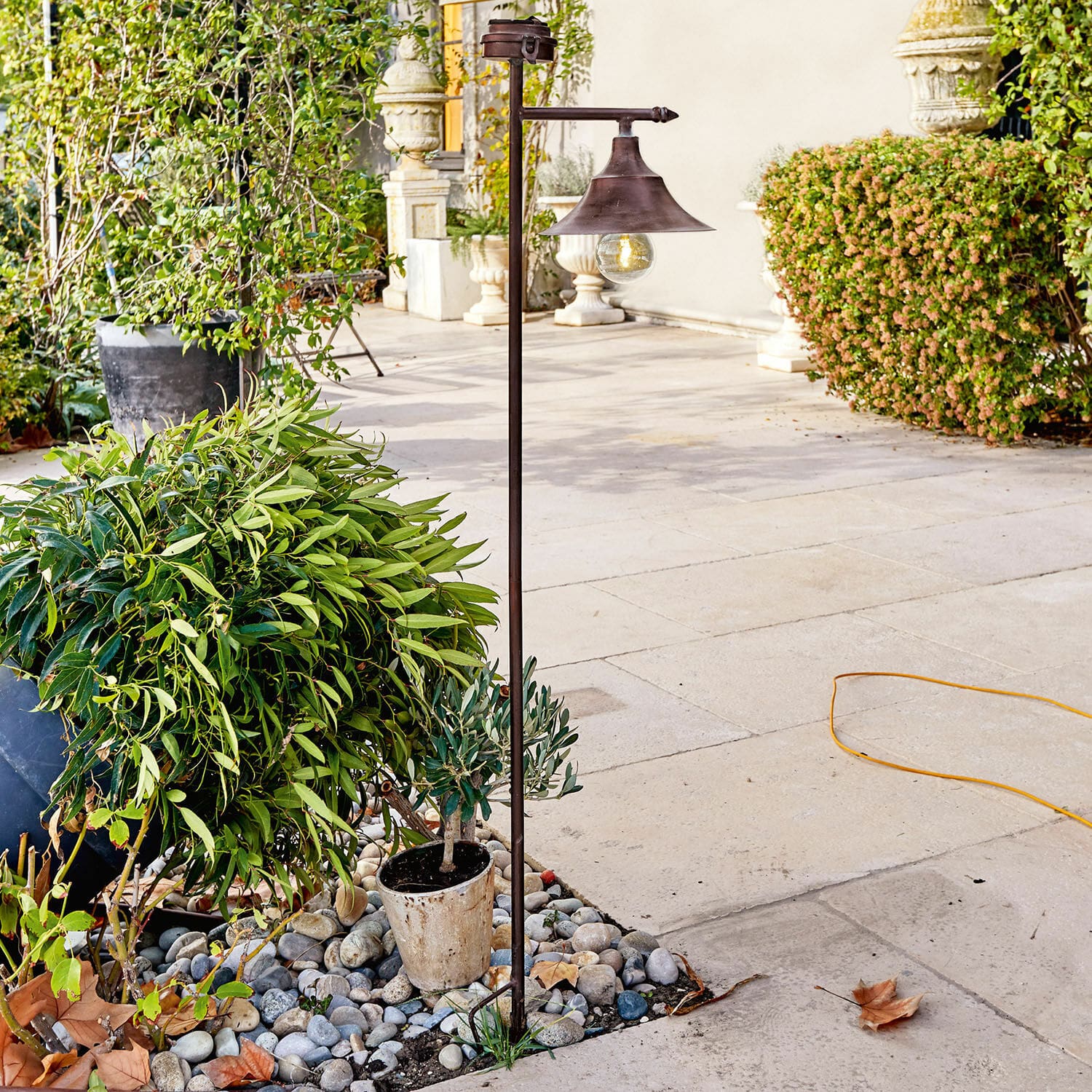 Lanterna solare Kaley Lampada da giardino in metallo color ruggine con lampadina, su pietre tra piante verdi