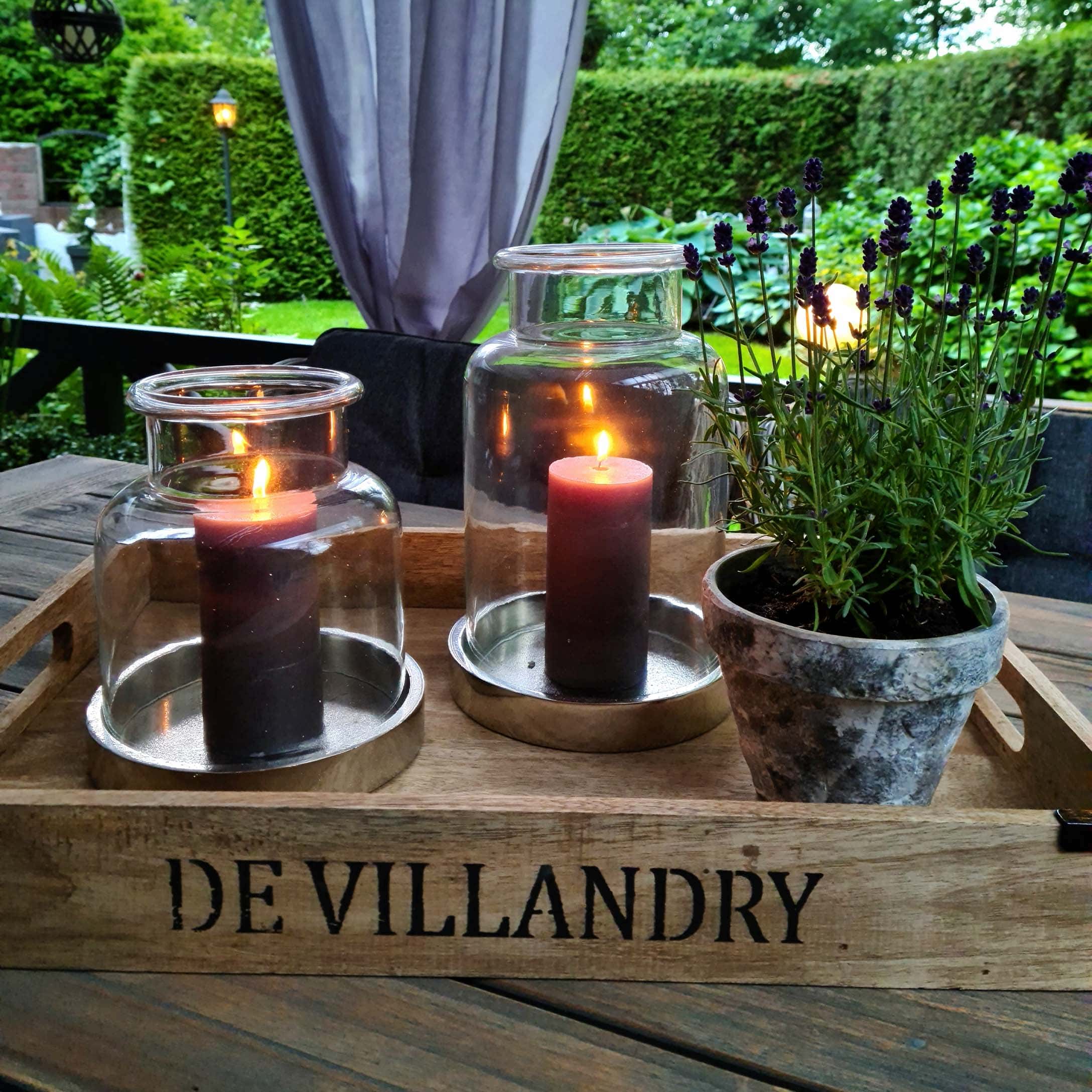 Vassoio in legno con due lanterne di vetro e vaso di lavanda su tavolo di legno in giardino