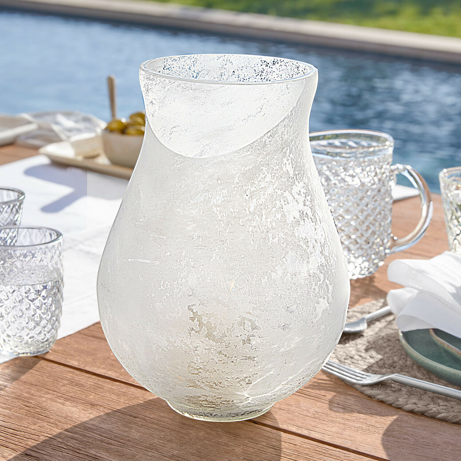 Portalumino Nareli Caraffa trasparente in vetro satinato su tavolo in legno vicino alla piscina, bicchiere elegante