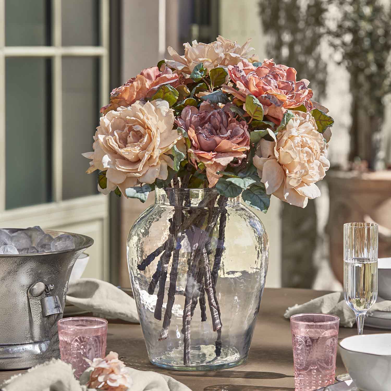 Mazetto di rose in vaso di vetro su tavolo, decorazione floreale in tonalità pastello