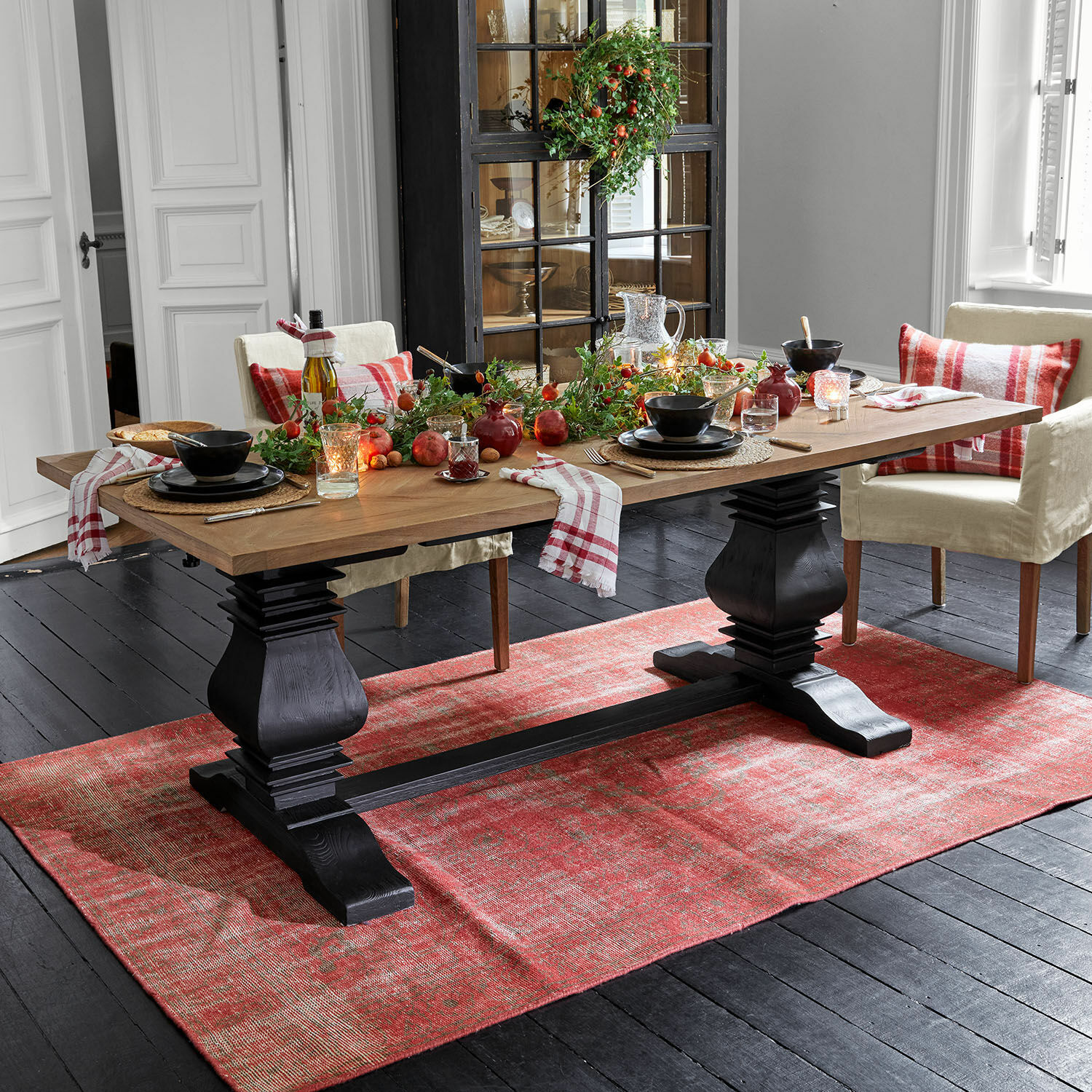 Tavolo Quillancourt Tavolo da pranzo con piano in legno e base nera su tappeto rosso, decorazioni festive