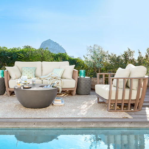 Set di mobili da giardino con cuscini beige e struttura in legno vicino alla piscina sulla terrazza