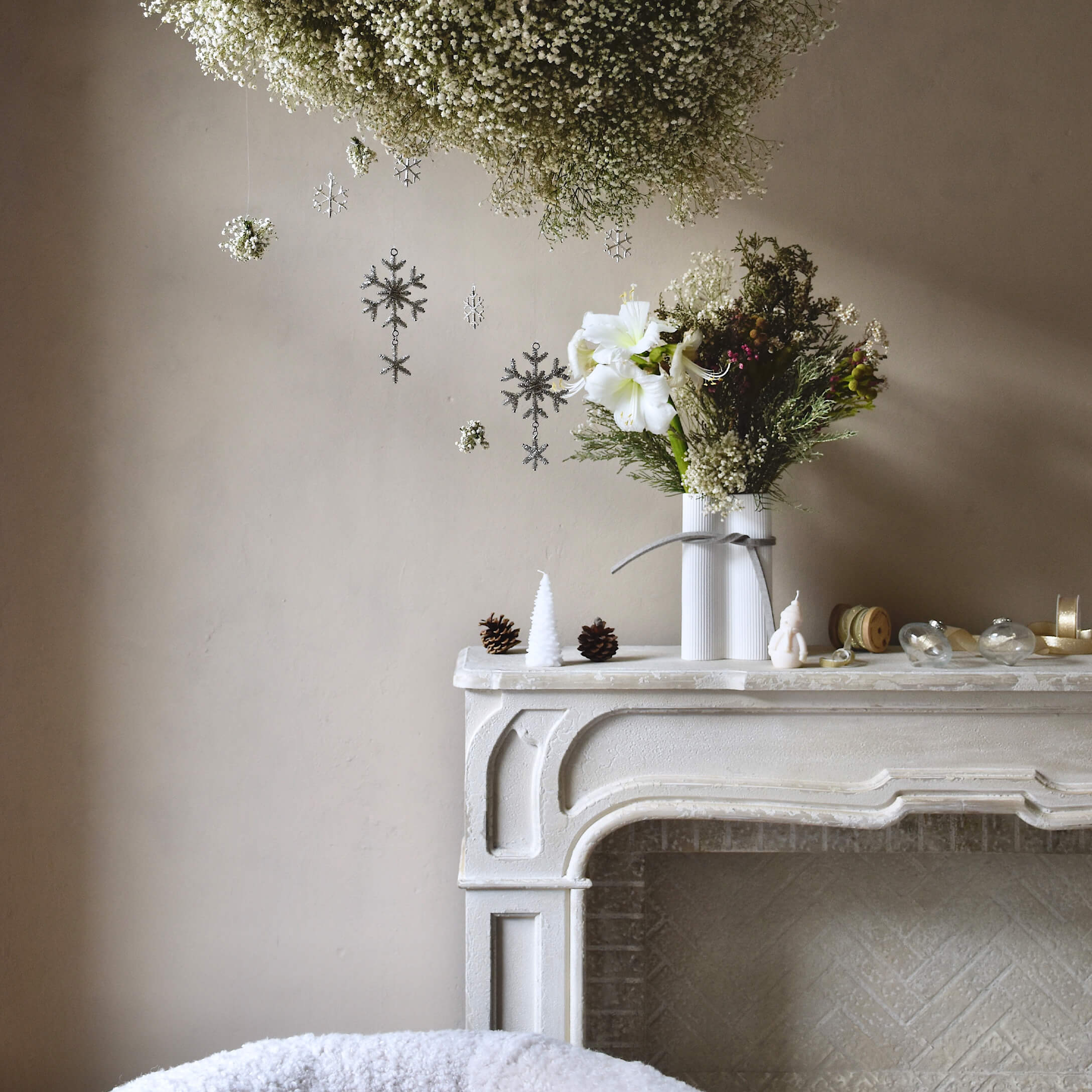Camino bianco decorativo con vaso e fiori, decorazioni natalizie con pigne e candele
