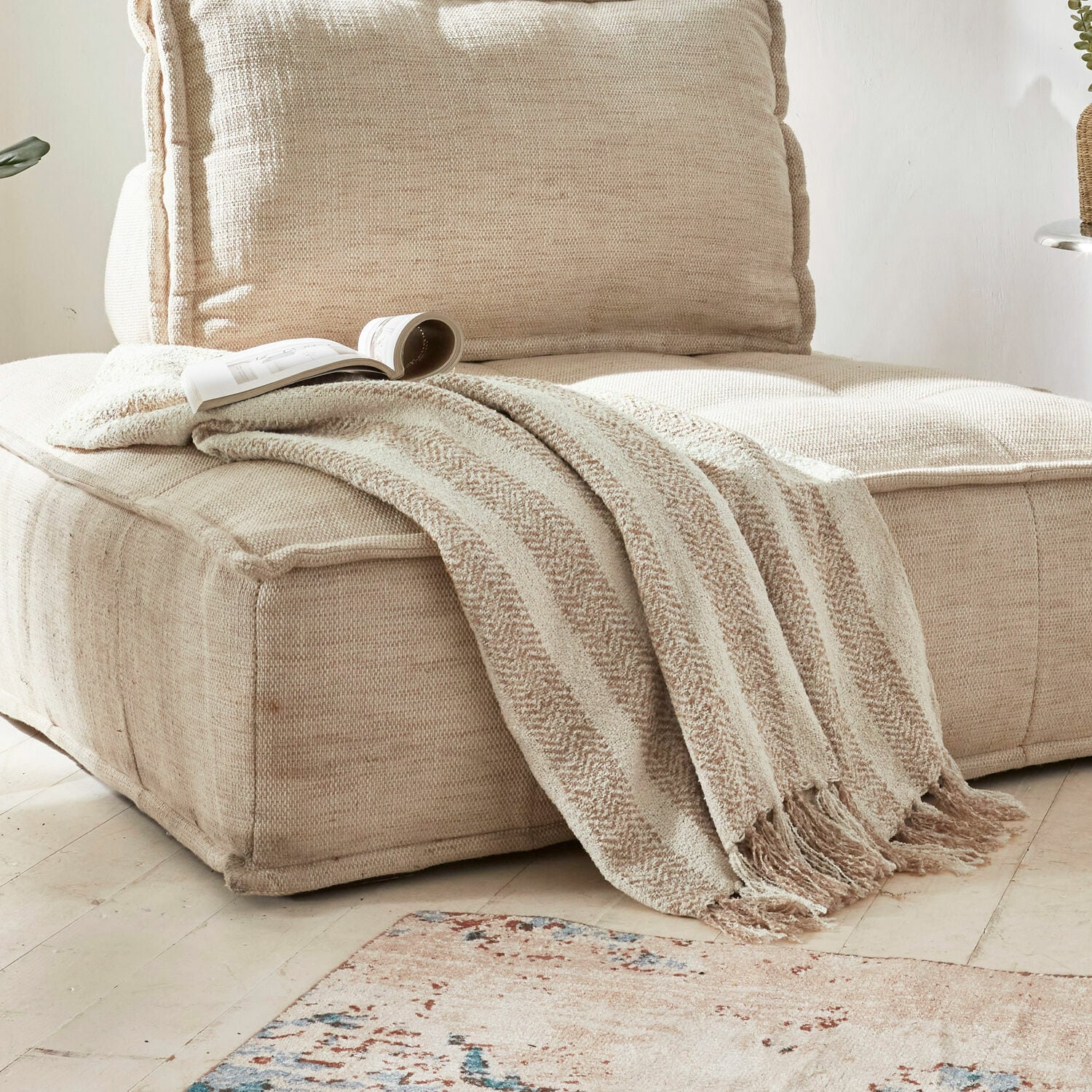 Coperta Aldan Coperta beige morbida con frange su divano in tessuto beige in soggiorno luminoso