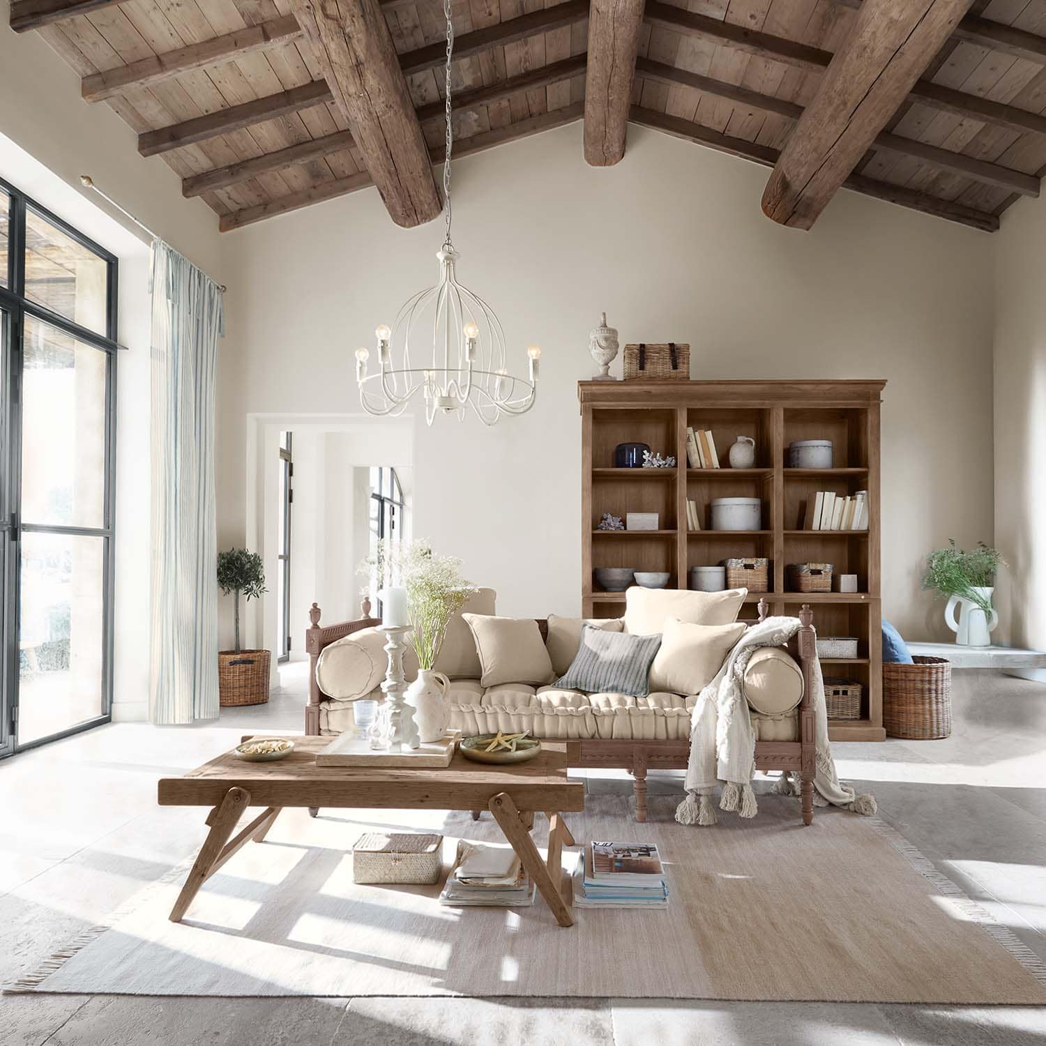 Soggiorno accogliente con tavolo in legno e divano beige sotto soffitto con travi in legno