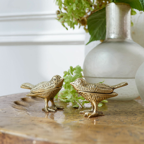 Due figure decorative di uccelli in metallo dorato su tavolo in legno, decorazione per interni