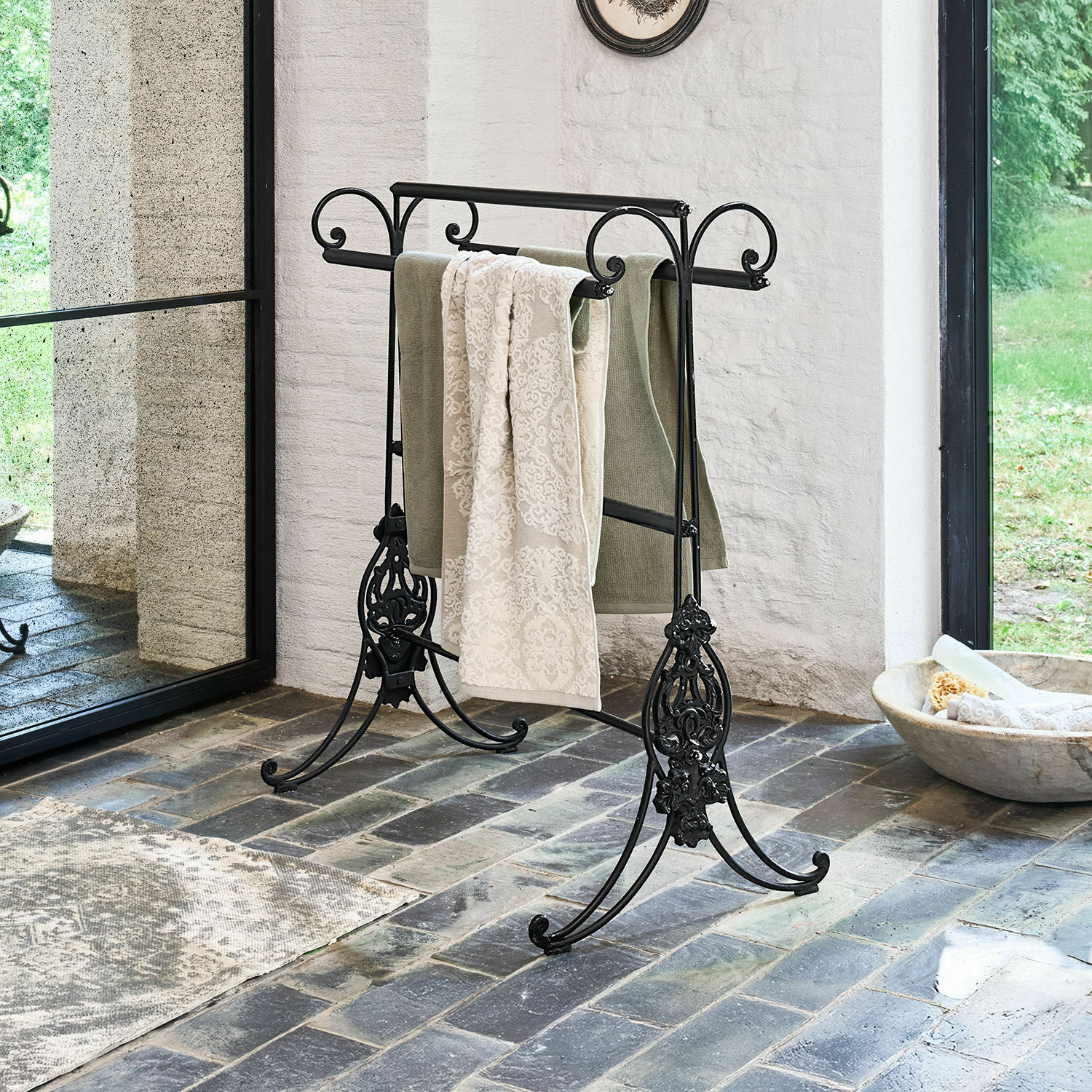 Porta asciugamani Tovrik Porta asciugamani in metallo nero con dettagli decorativi su pavimento in pietra in ambiente luminoso