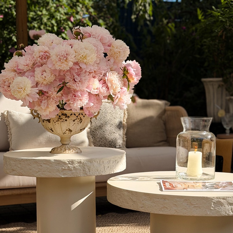 Bouquet decorativo di peonie rosa in vaso di ceramica su tavolo chiaro in giardino con luce naturale