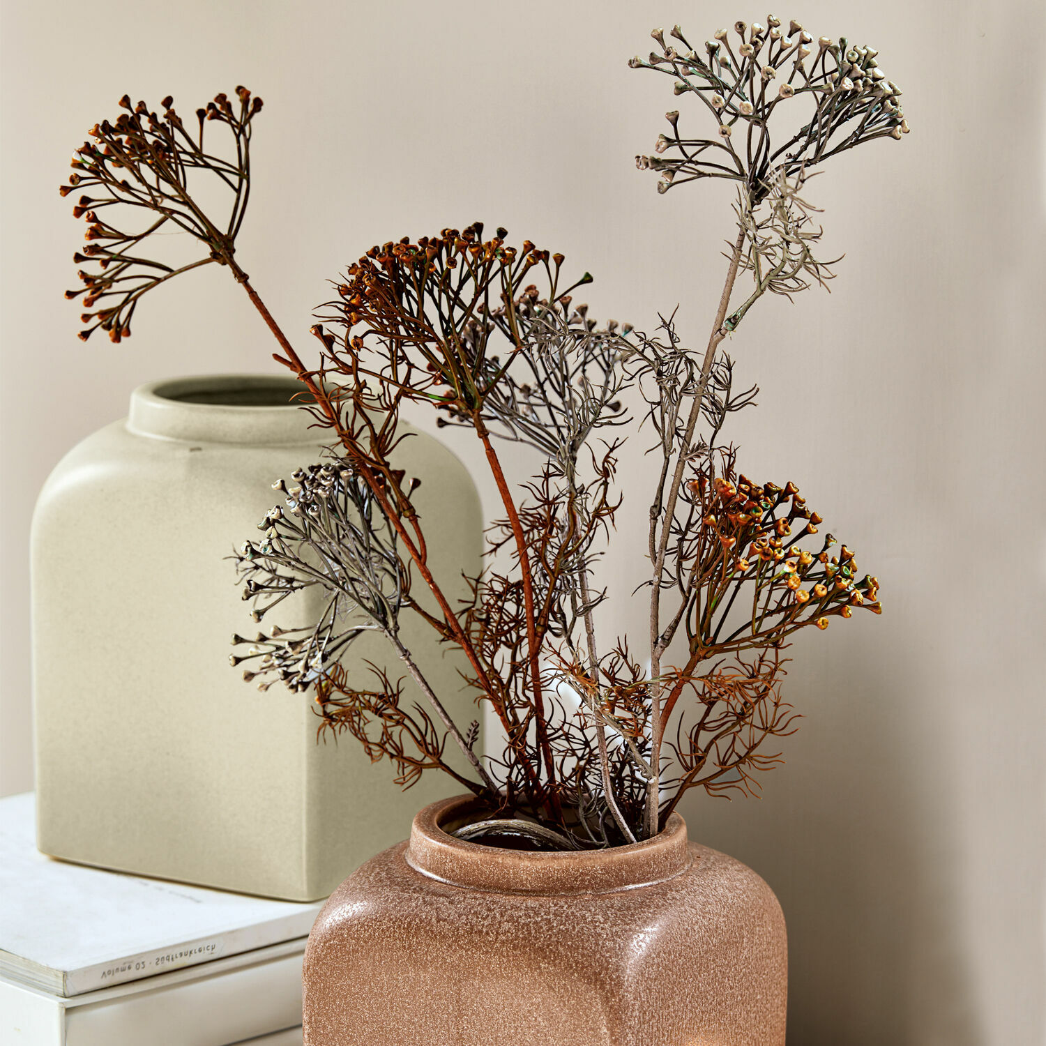 Set di 4 fiori decorativi Jennings Vaso in ceramica marrone con fiori secchi davanti a decorazioni beige e libri