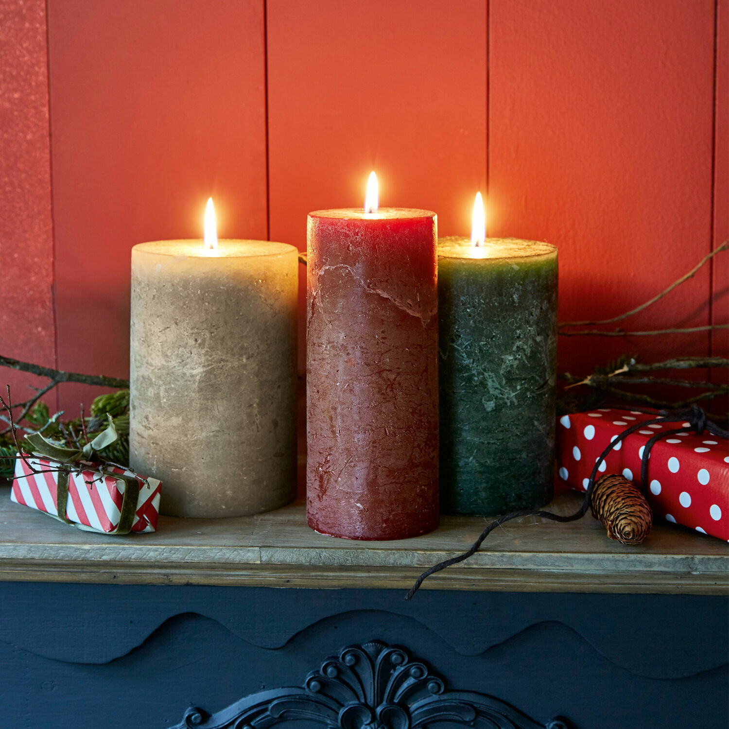 Set di 3 candele Salis Tre candele di cera beige, rossa e verde su una mensola di legno con decorazioni natalizie