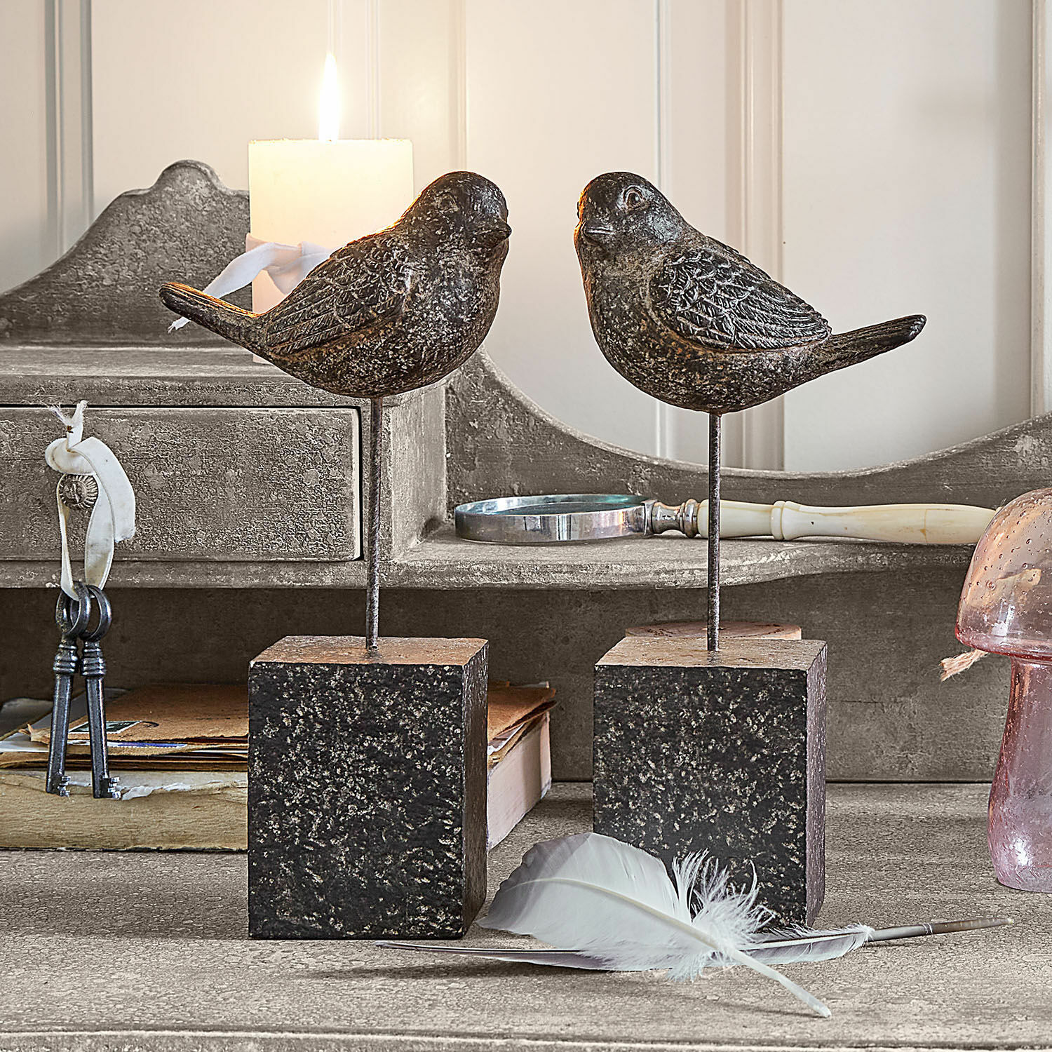 Coppia di uccellini decorativi Juxivel Uccelli decorativi in metallo scuro su basi quadrate su tavolo rustico con piuma bianca