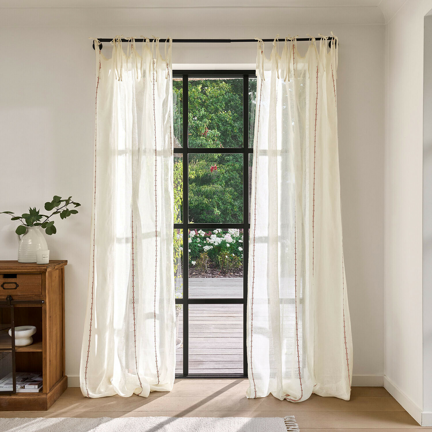 Tende trasparenti crema con delicato motivo rosso, tessuto leggero davanti a grande finestra