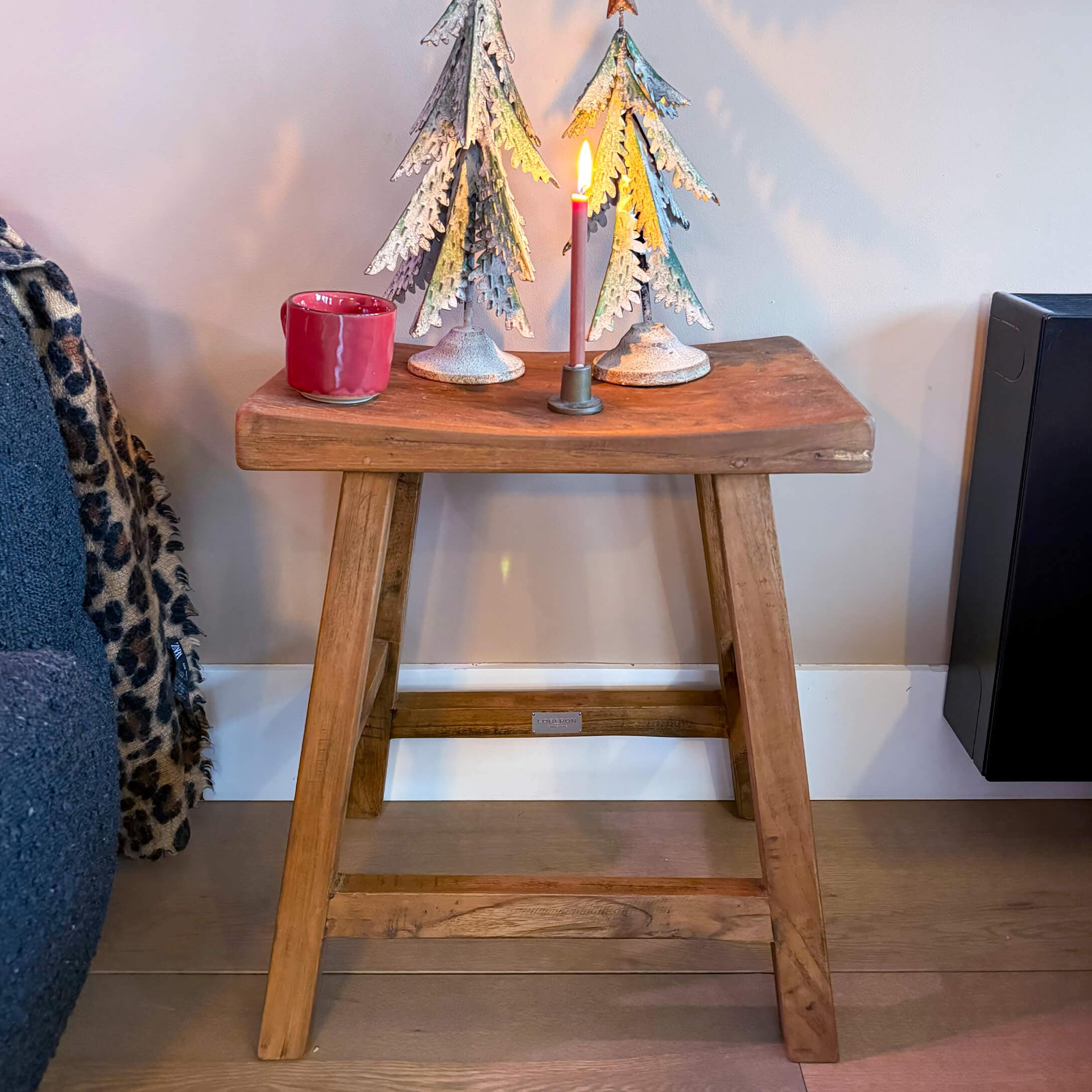 Sgabello in legno con alberi di metallo decorativi e candela accesa in stile industriale