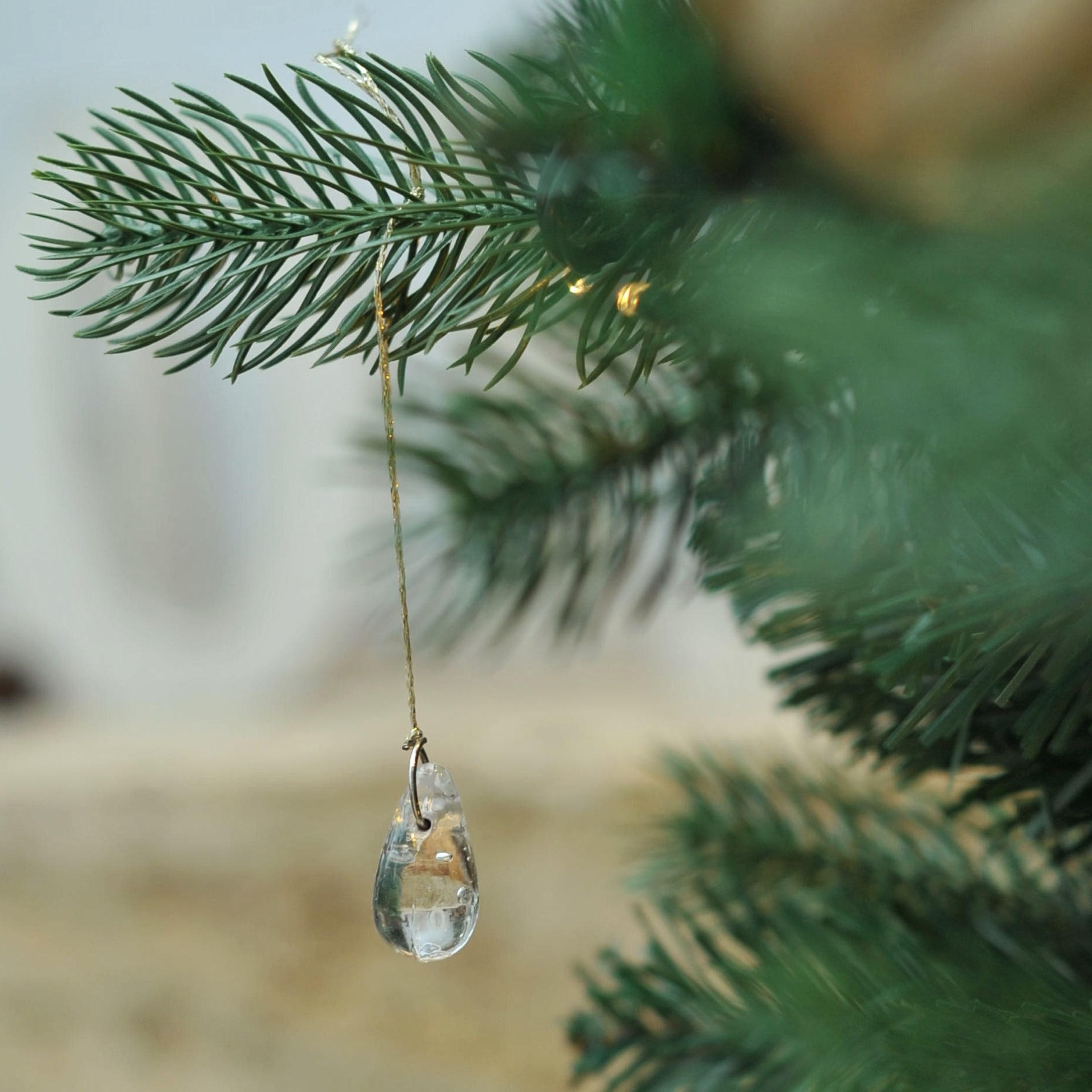Decorazione in vetro trasparente appesa a ramo verde di albero di Natale in veranda