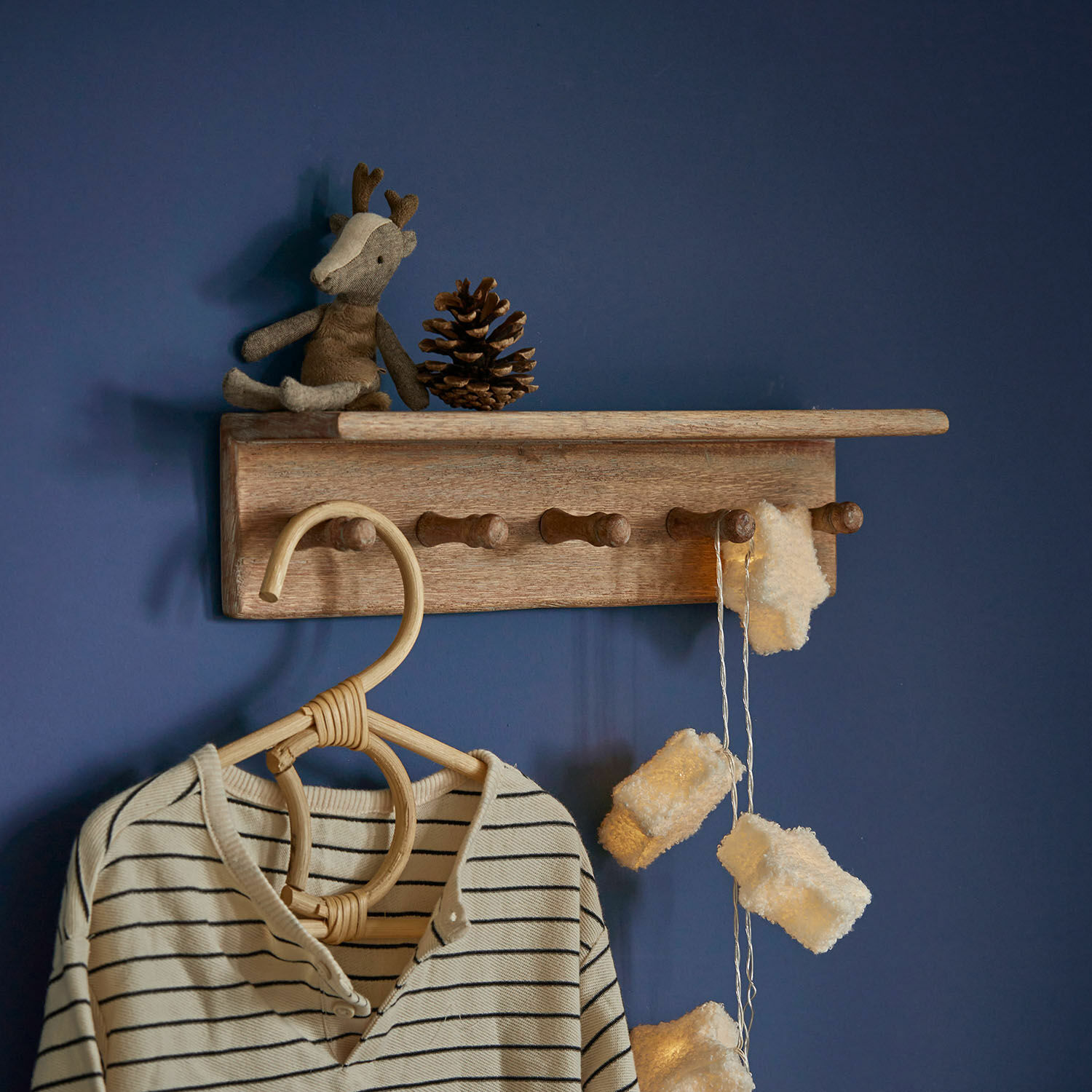 Scaffale da parete Norellan Appendiabiti da parete in legno con ganci, peluche renna e luci decorative su parete blu