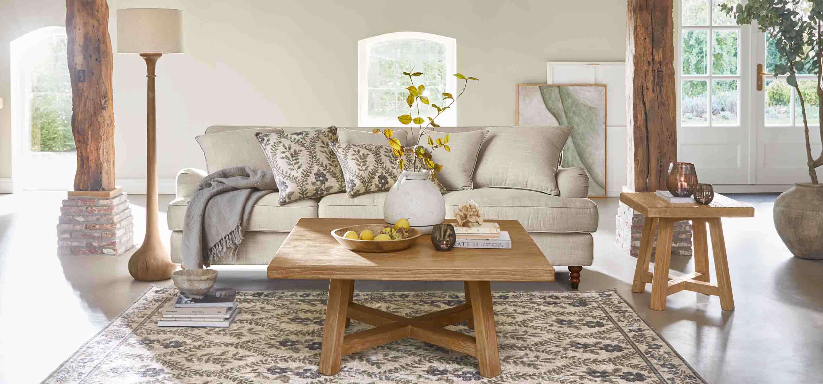 Soggiorno accogliente con divano beige, tavolino in legno e decorazioni naturali