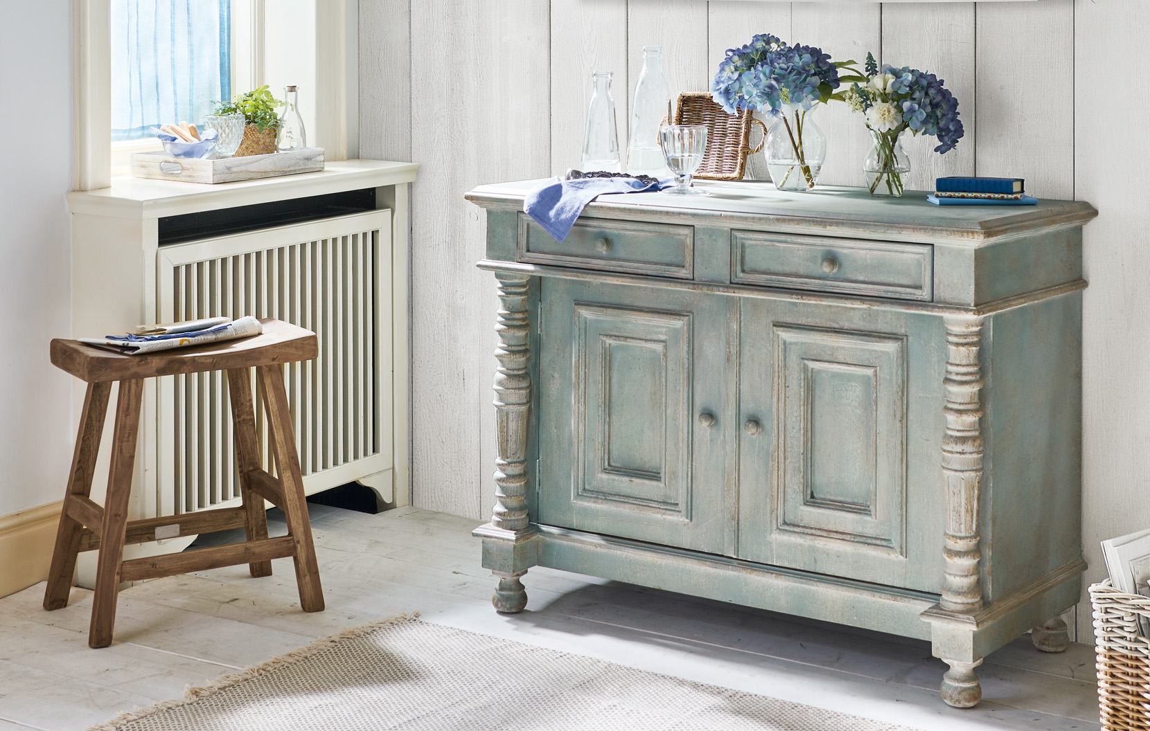 Credenza shabby chic in legno verde-grigio con fiori decorativi e bottiglie di vetro