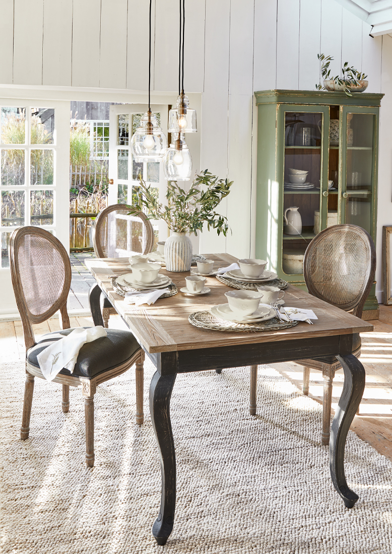 Sala da pranzo con tavolo in legno e sedie in vimini vintage, luce naturale e decorazioni eleganti
