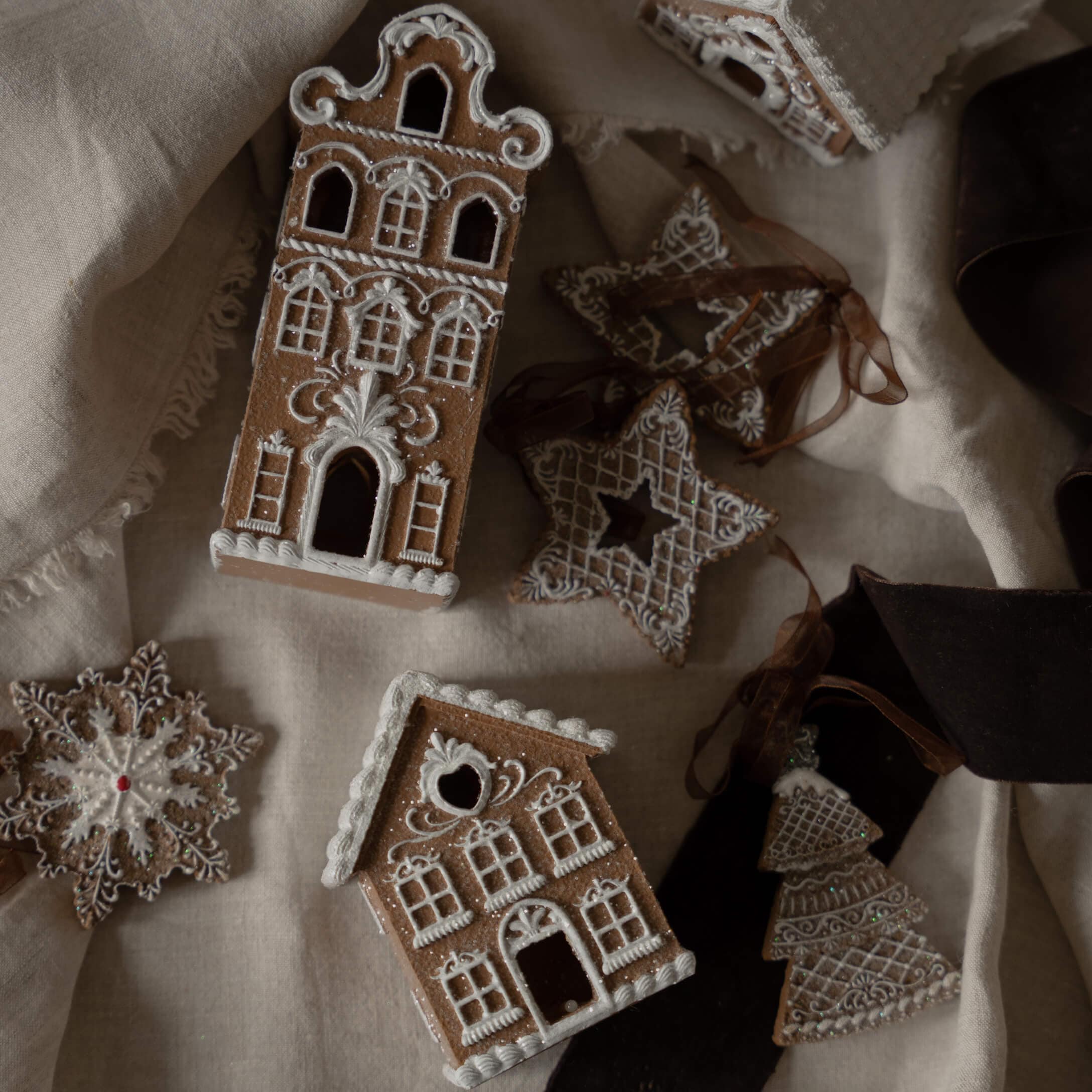 Case e stelle di pan di zenzero decorate con glassa bianca su tessuto di lino, decorazioni natalizie