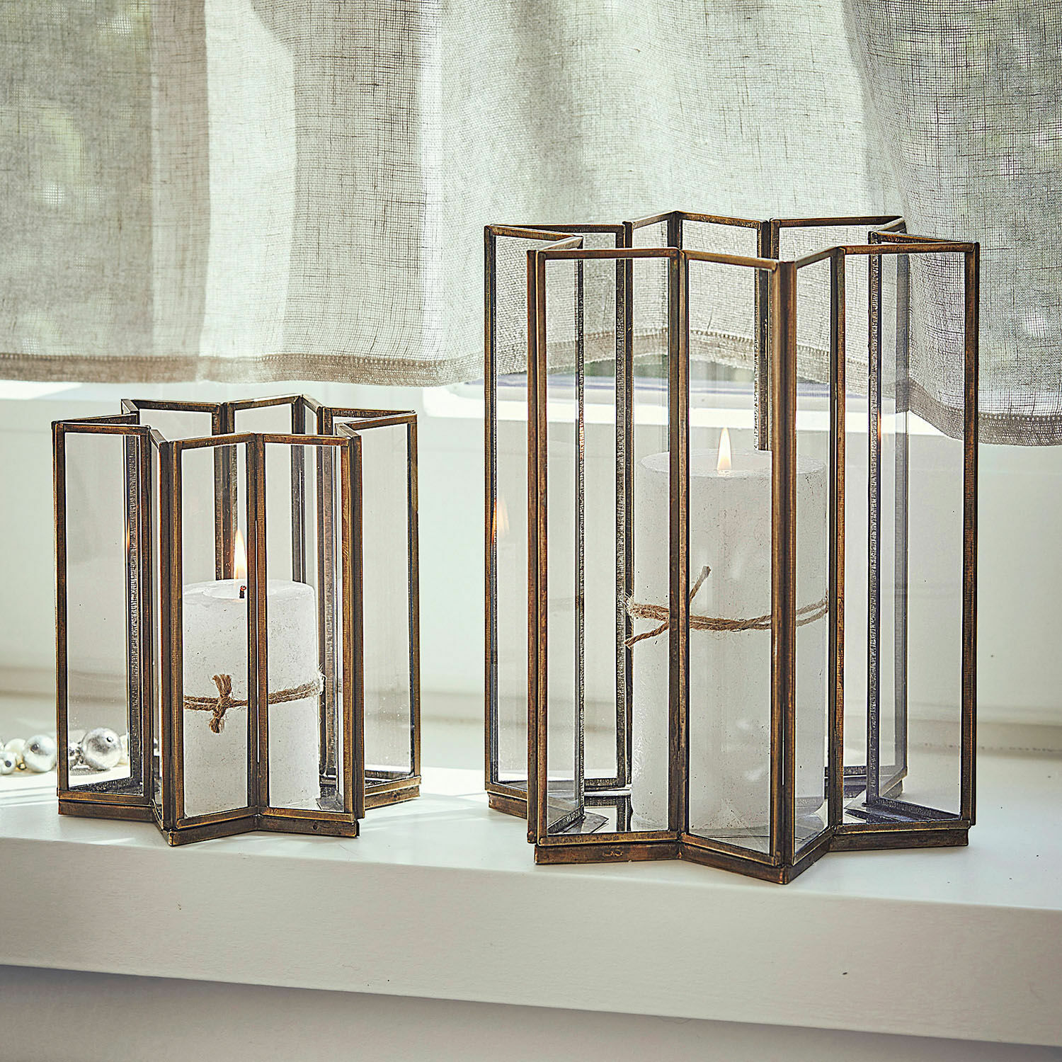 Coppia di portacandele Créon Set di due lanterne in metallo e vetro color ottone con candele bianche sul davanzale