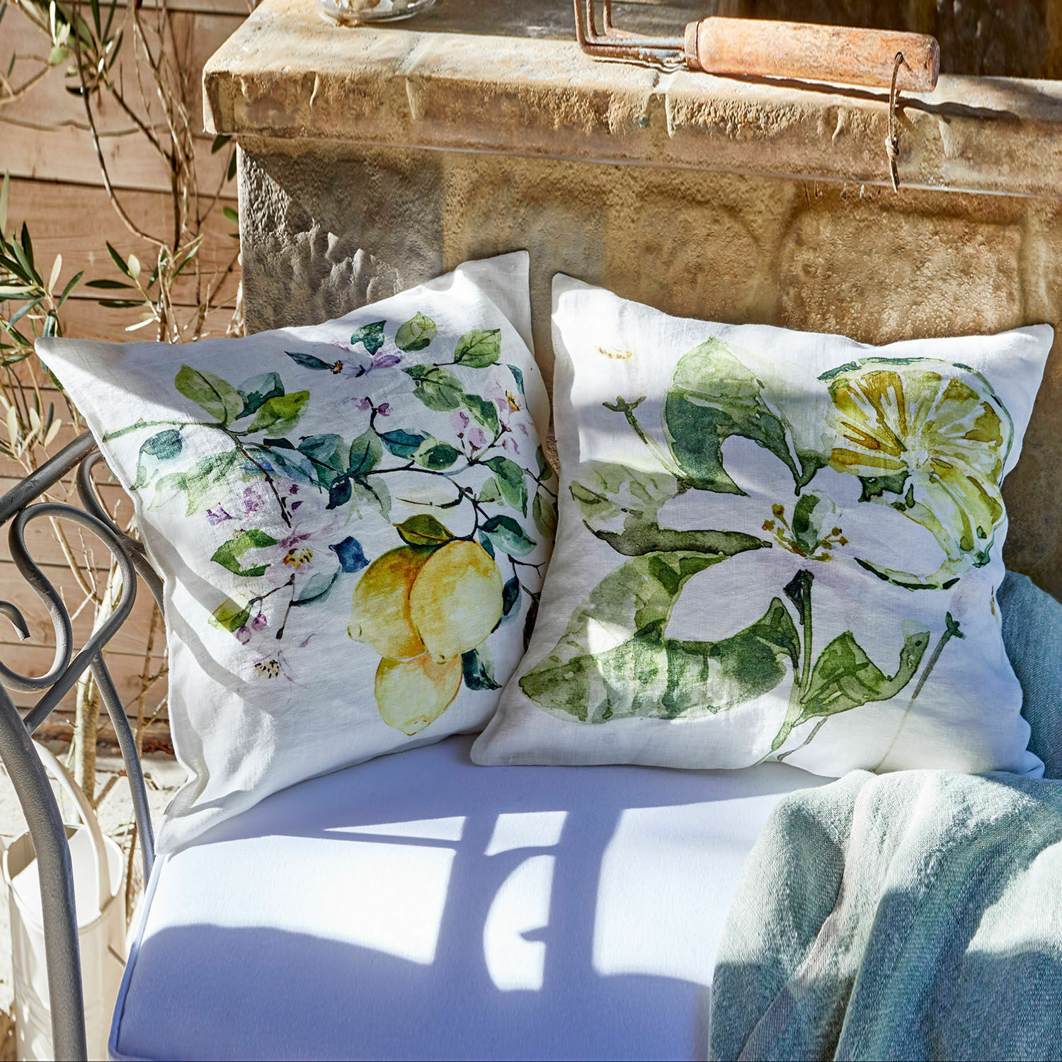 Cuscini in lino bianco con stampa di limoni e foglie verdi, decorazione da giardino su panca in metallo