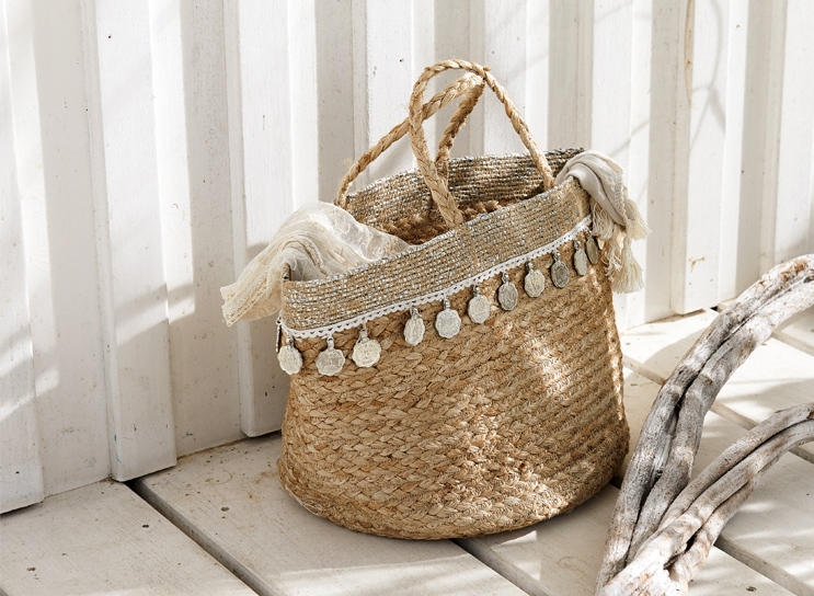 Cesto boho in materiale naturale intrecciato con monete decorative e sciarpa chiara, decorazione d'interni.